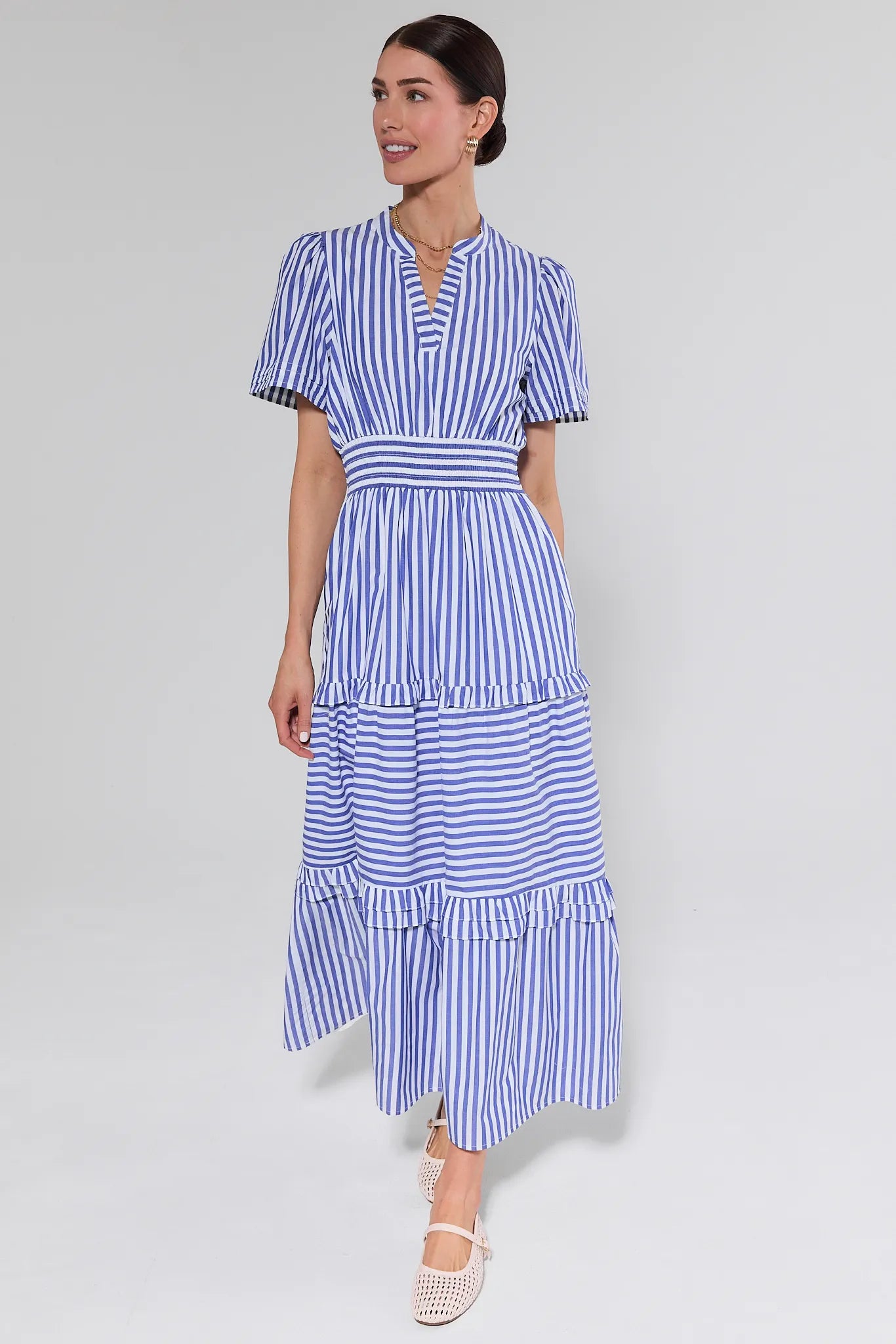 Woman wearing a blue and white striped dress on a gray background