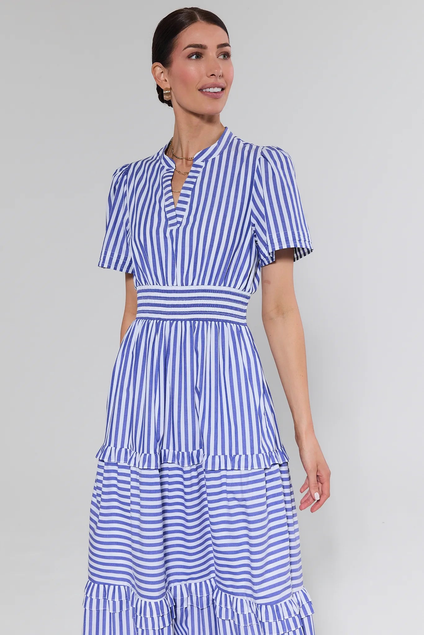 Woman wearing a blue and white striped dress on a plain background