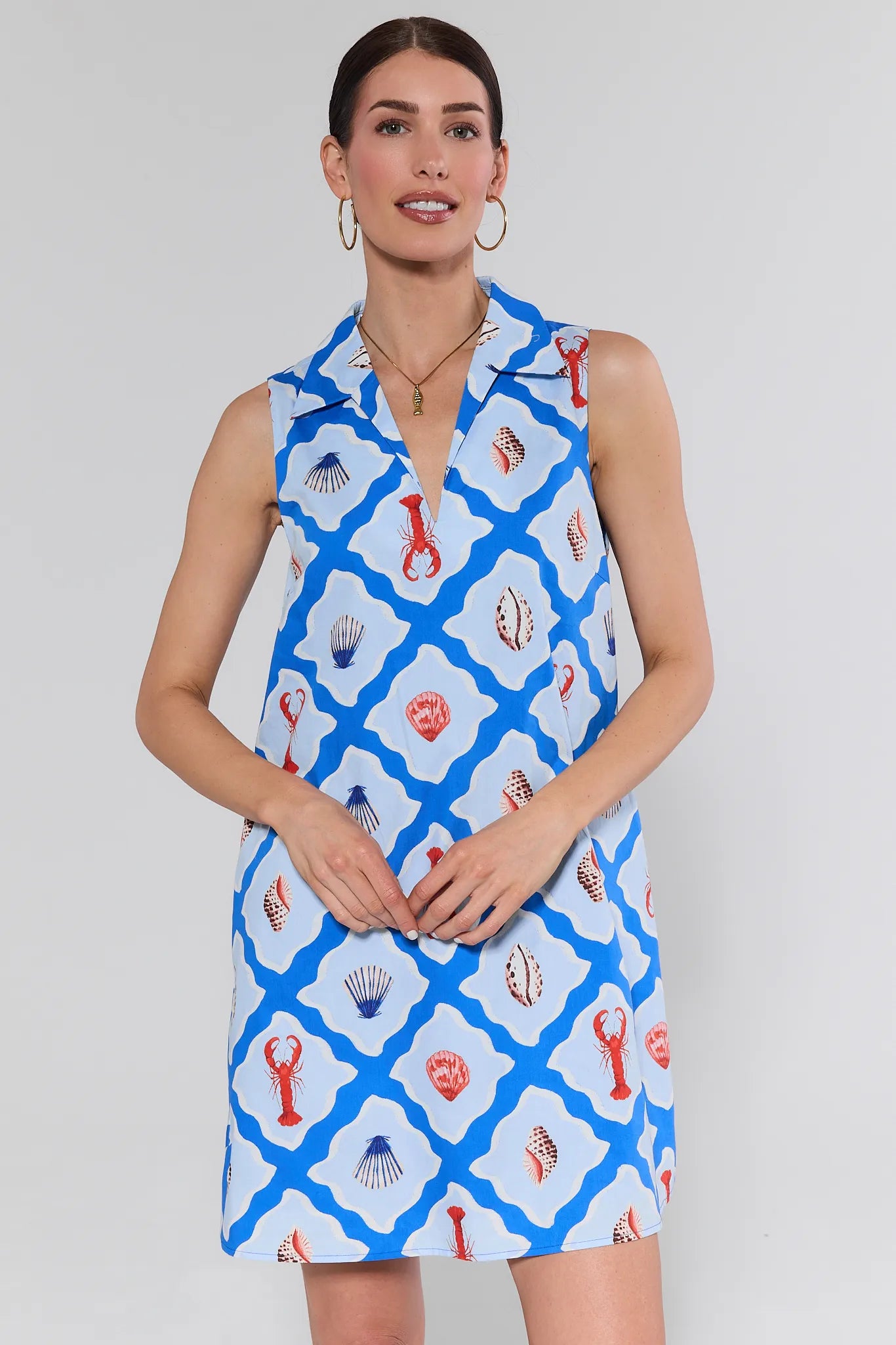 Woman wearing a sleeveless dress with shell pattern on a plain background