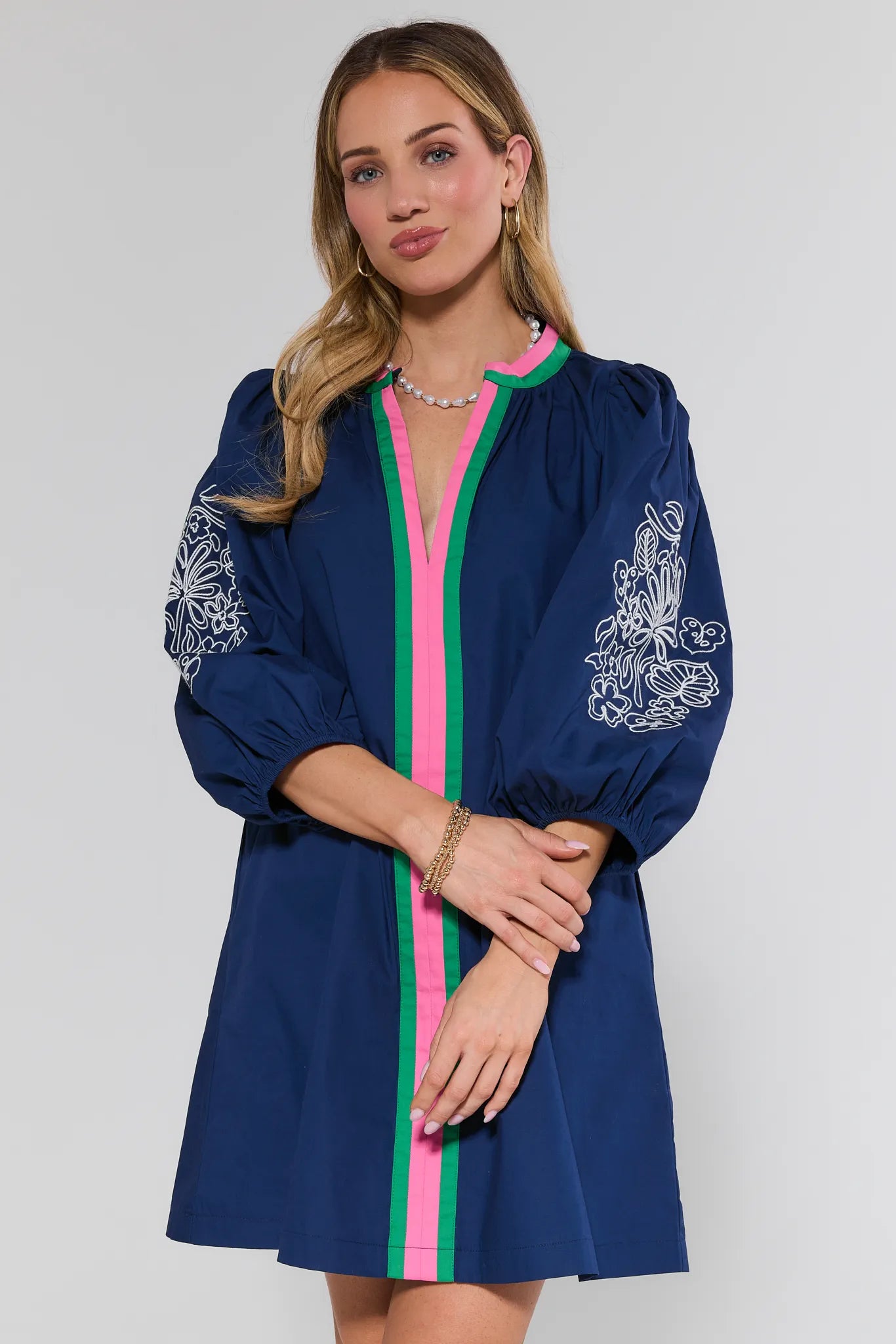 Woman wearing a blue dress with pink and green accents on a white background