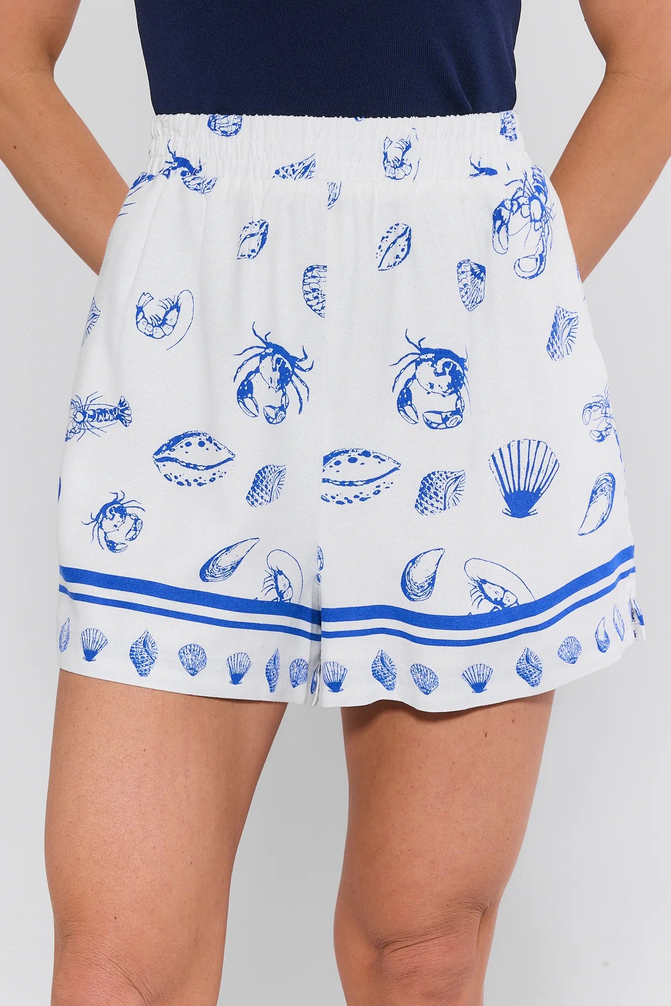 White skirt with blue shell pattern worn by a person on a white background