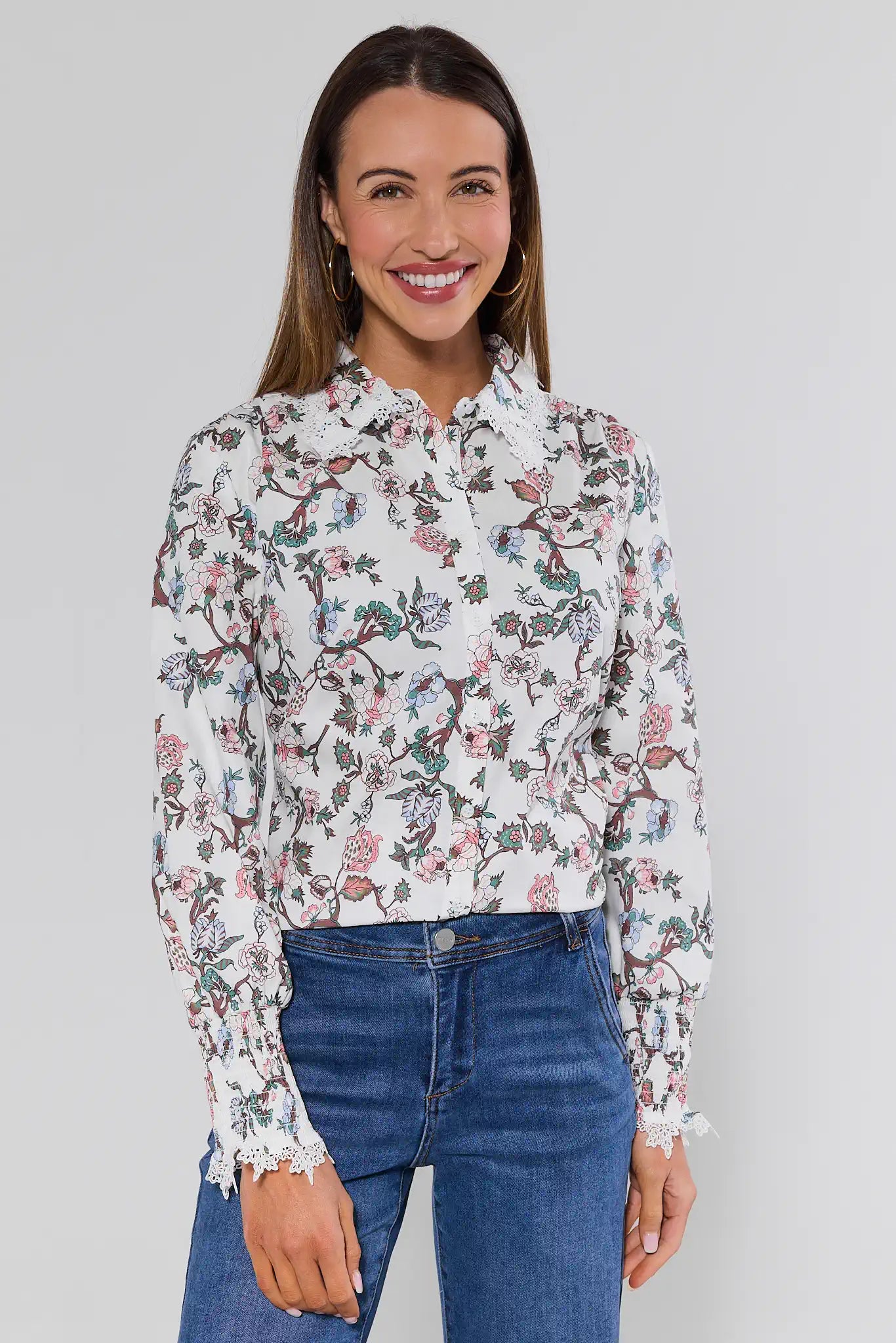 Woman wearing a floral blouse and blue jeans against a plain background
