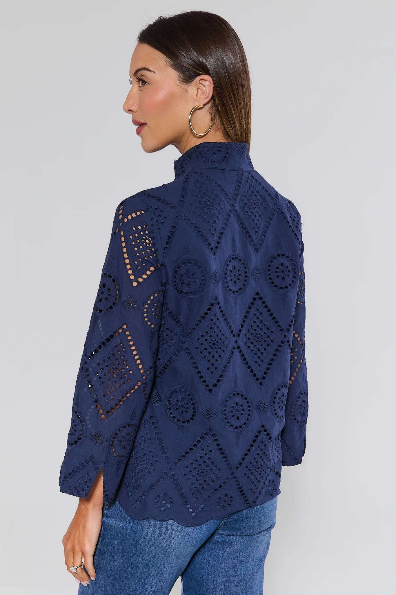 Woman wearing a navy blue crochet top with geometric patterns on a plain background