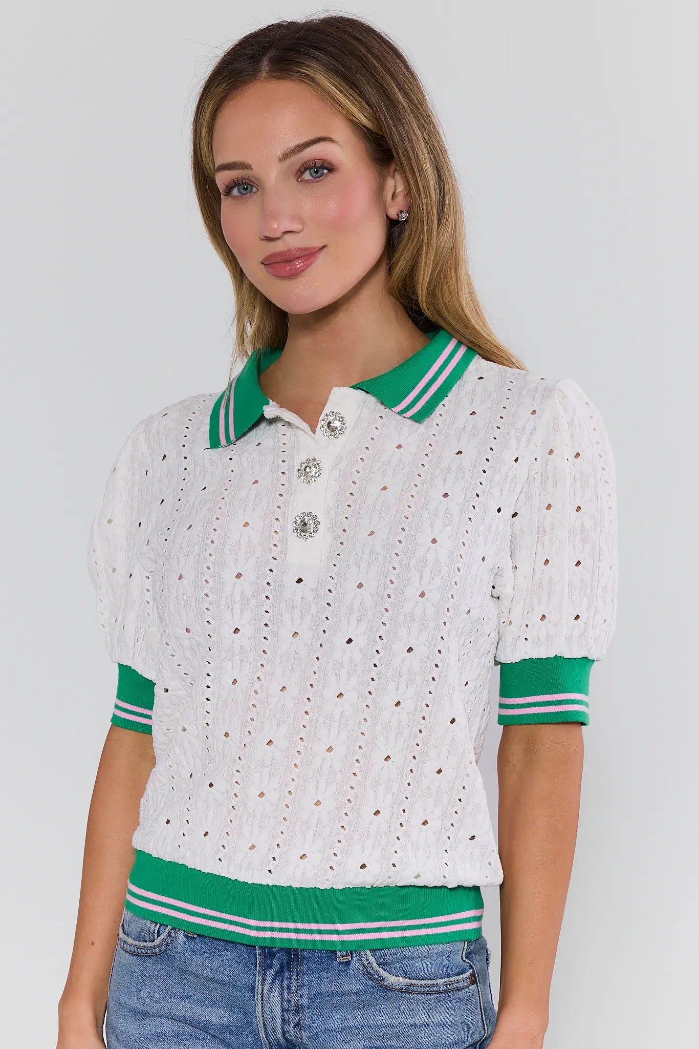Woman wearing a white and green polka dot blouse with blue jeans on a plain background