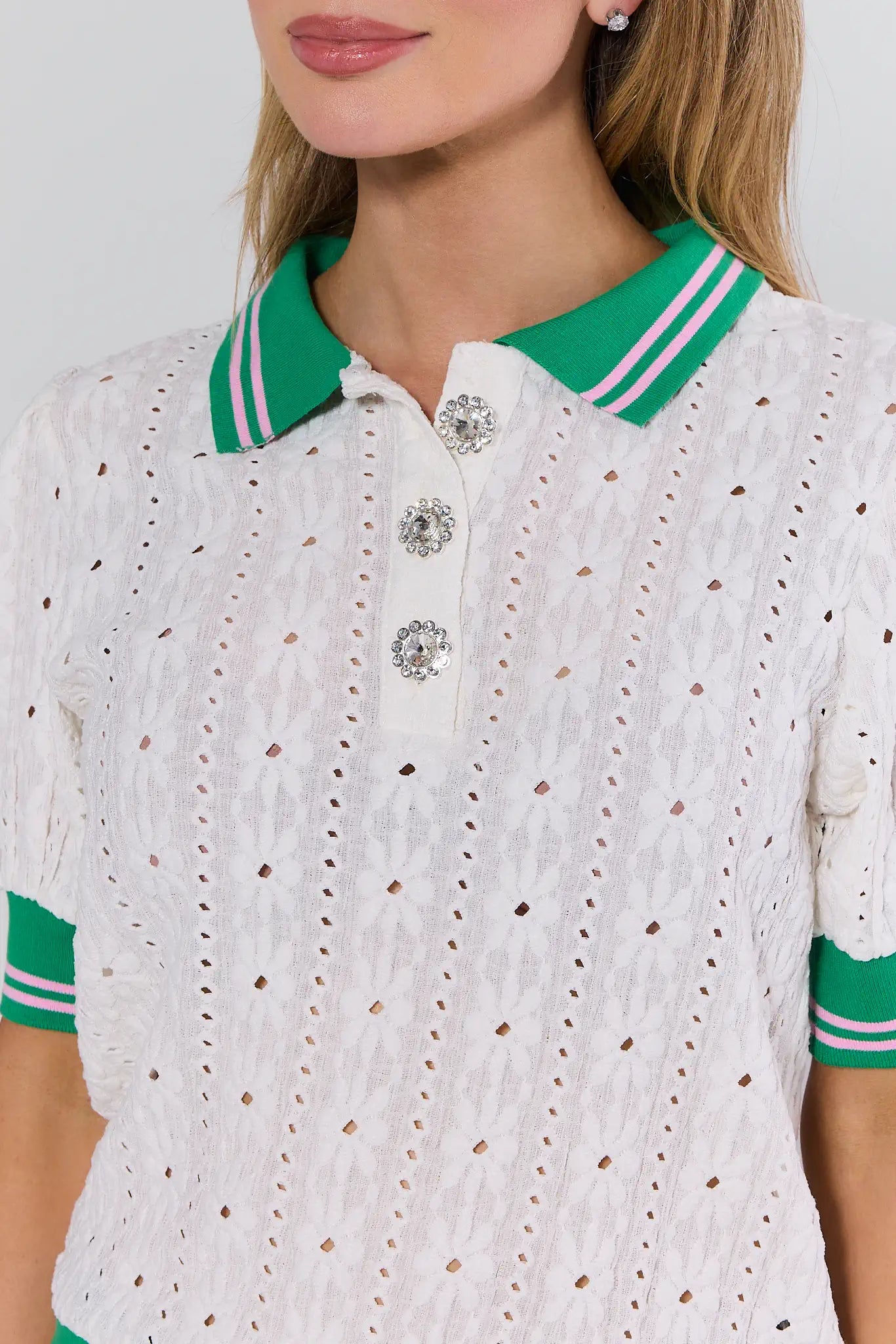 White embroidered polo shirt with green accents worn by a person