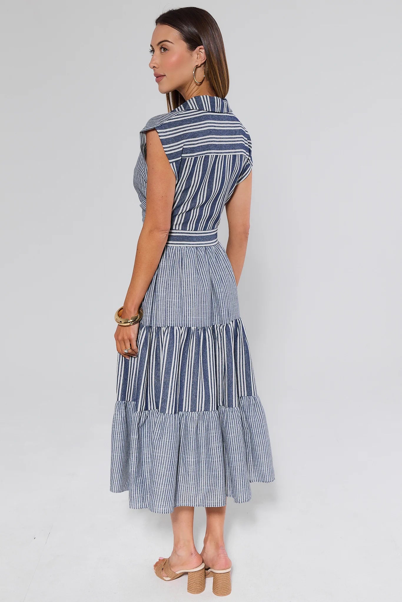 Woman wearing a blue and white striped dress on a plain background