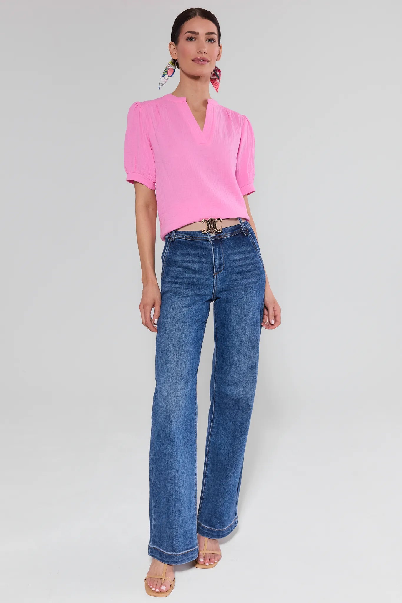 Woman wearing a pink blouse and blue jeans on a white background