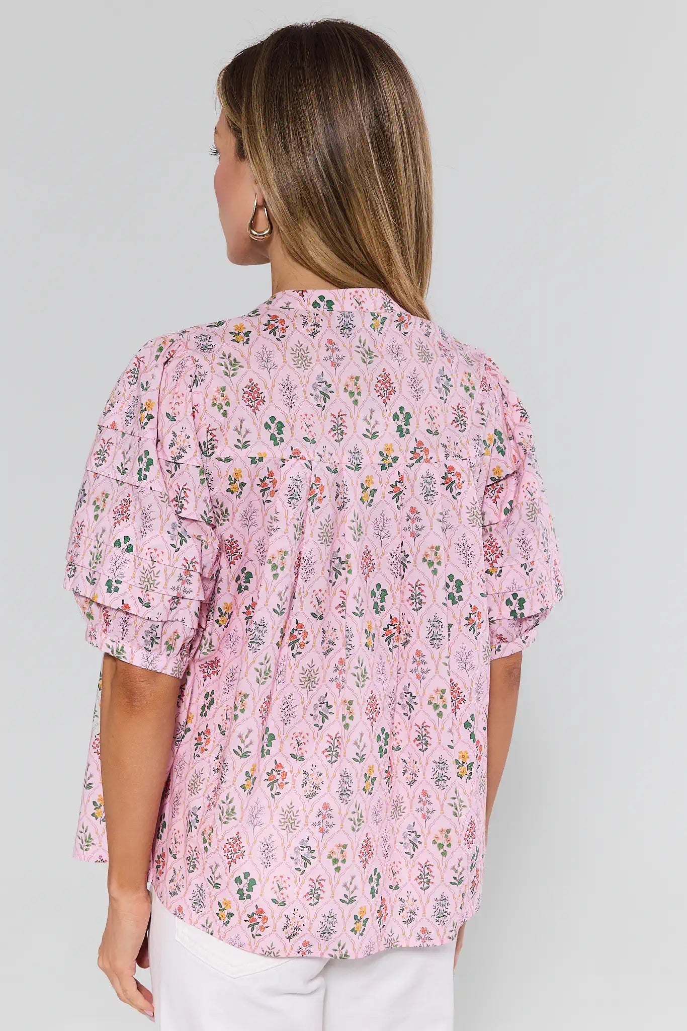 Woman wearing a pink floral blouse against a background