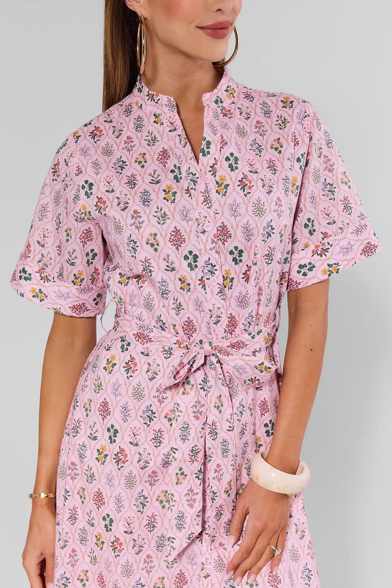 Woman wearing a pink floral dress on a gray background