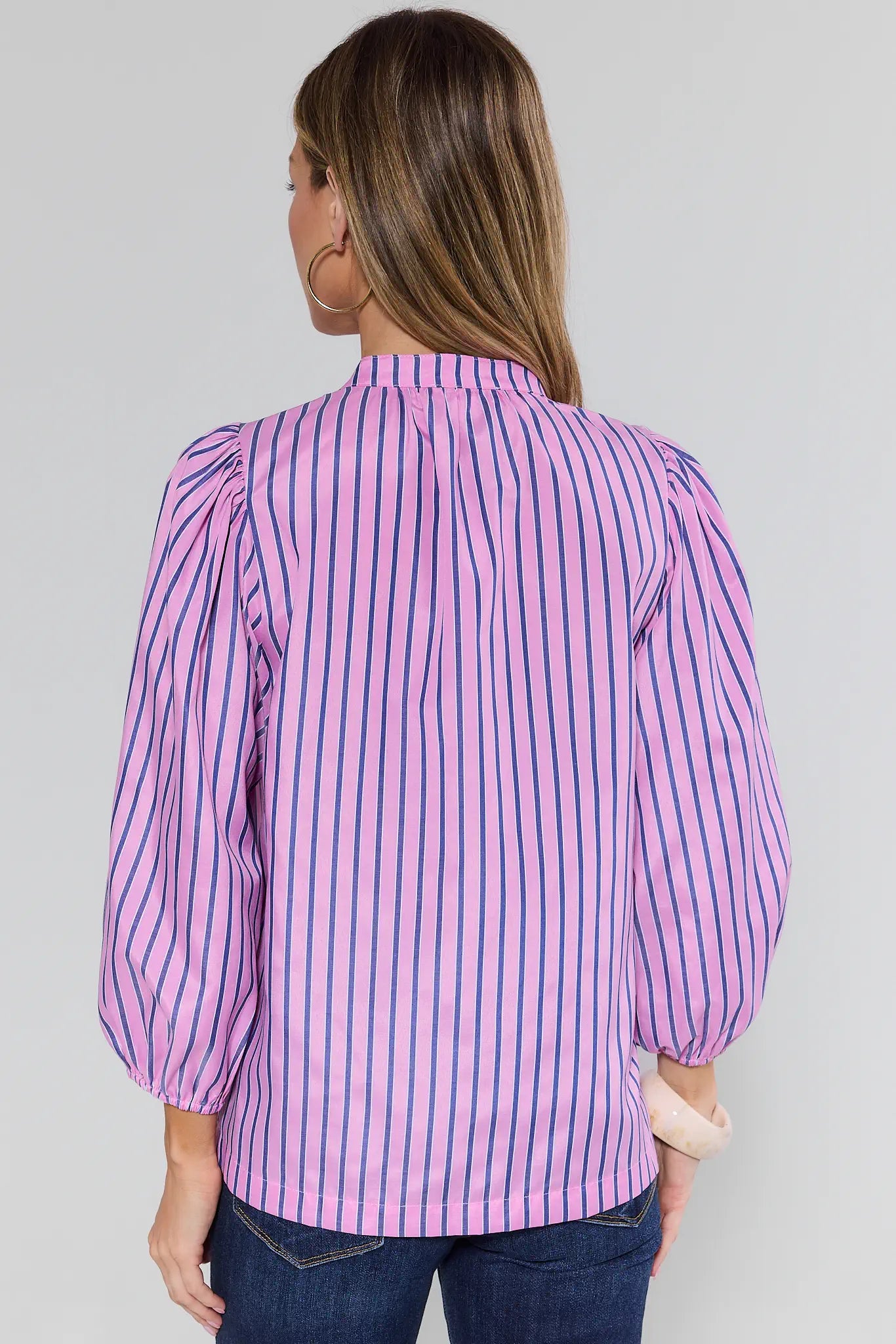 Woman wearing a purple and white striped blouse against a gray background