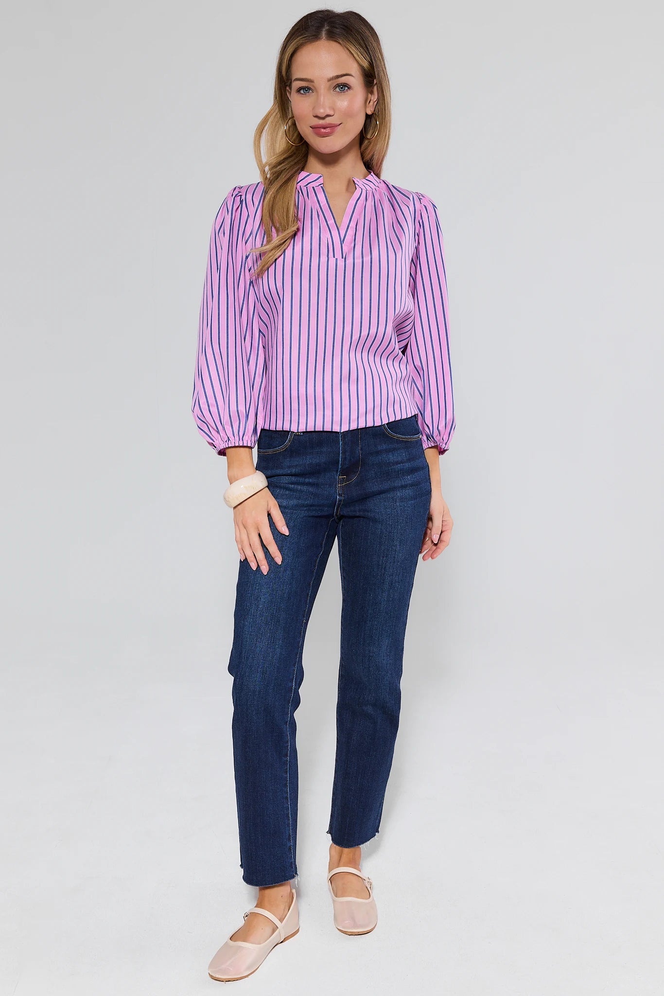 Woman wearing a purple striped shirt and blue jeans on a white background
