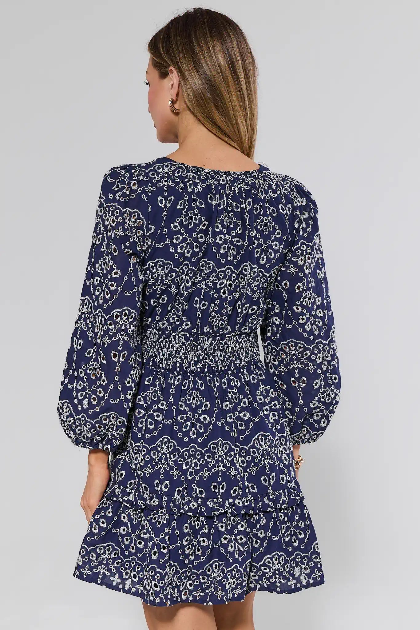 Woman wearing a navy blue dress with white floral pattern on a plain background