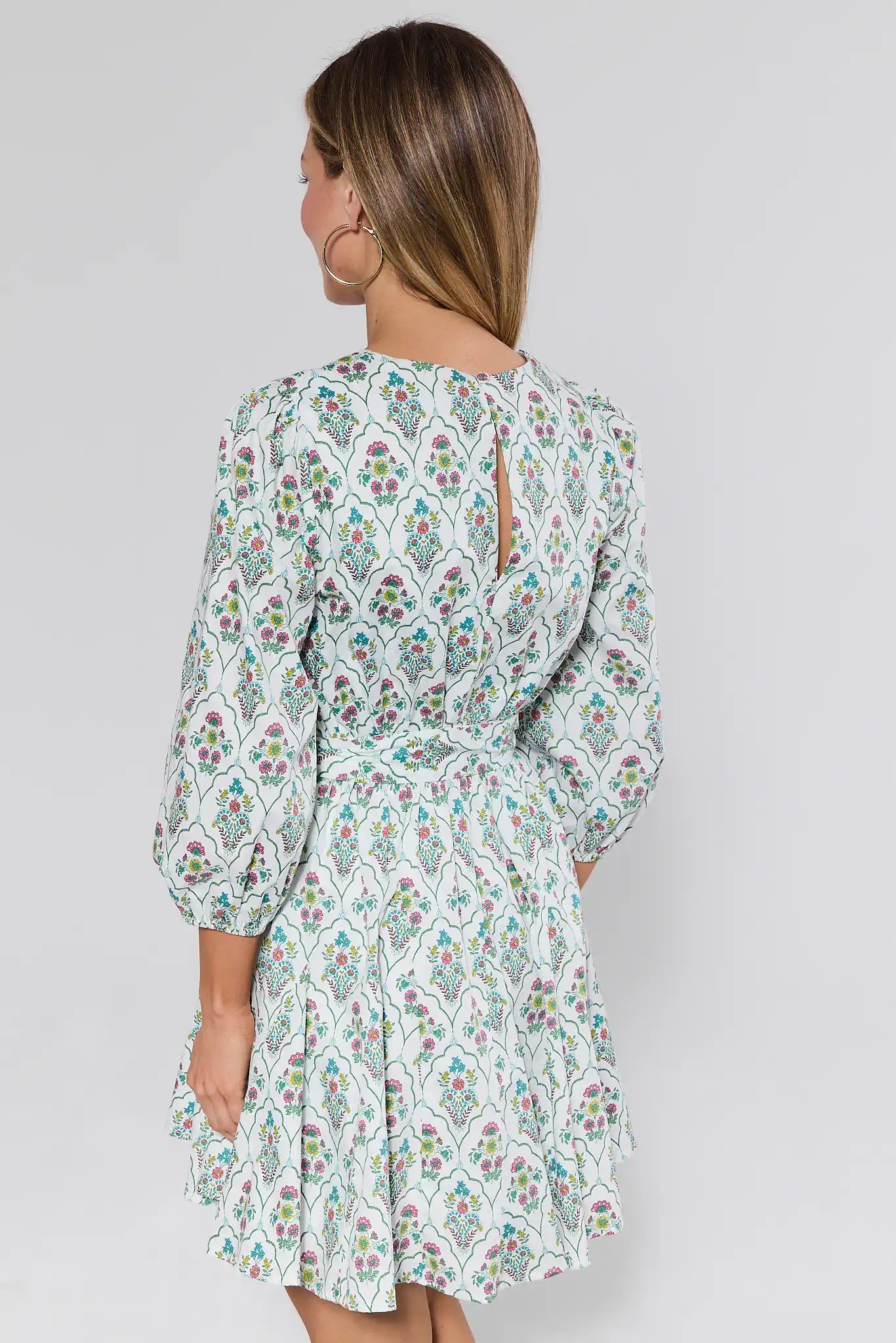 Woman wearing a floral dress against a plain background