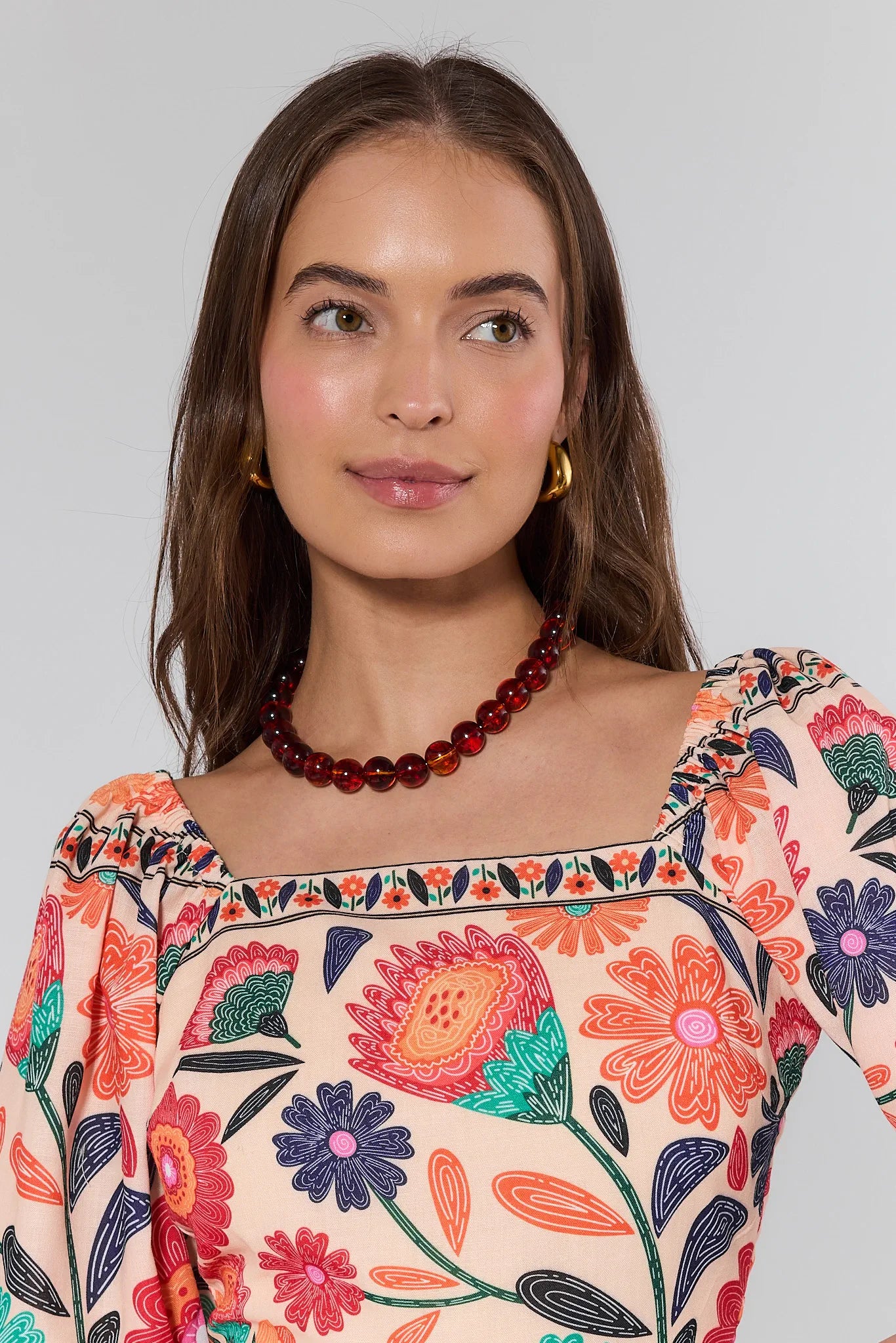 Woman wearing a colorful floral blouse with a plain background