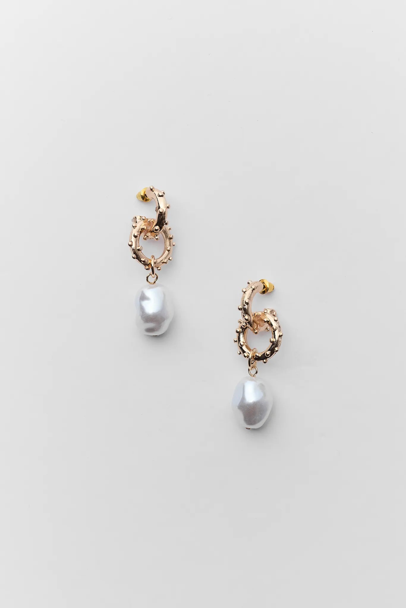 Pair of pearl earrings with gold accents on a light gray background