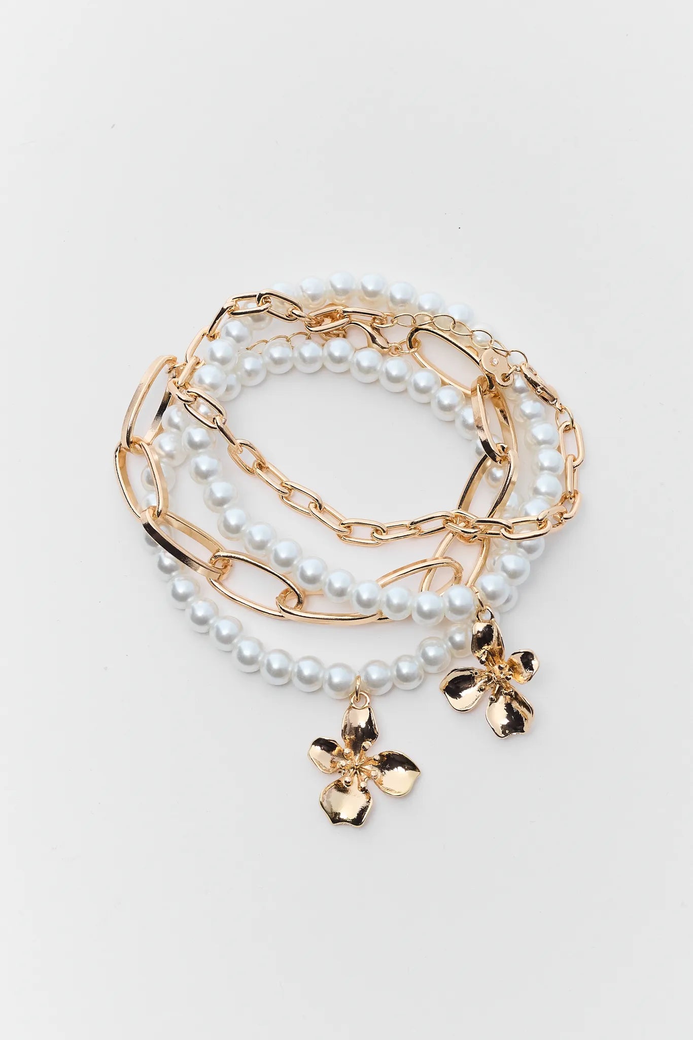 Set of pearl and gold chain bracelets on a light gray background