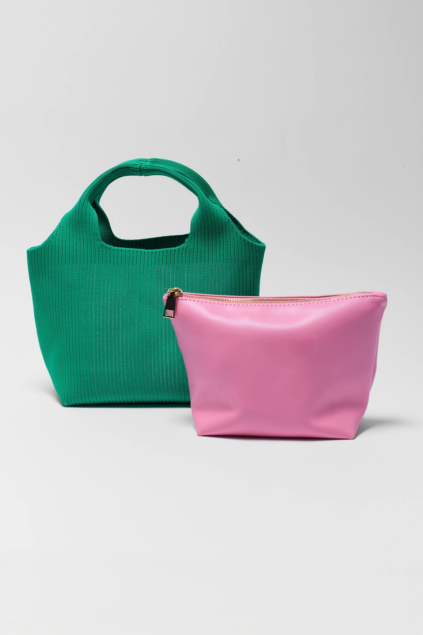 Green handbag and pink pouch on a light gray background