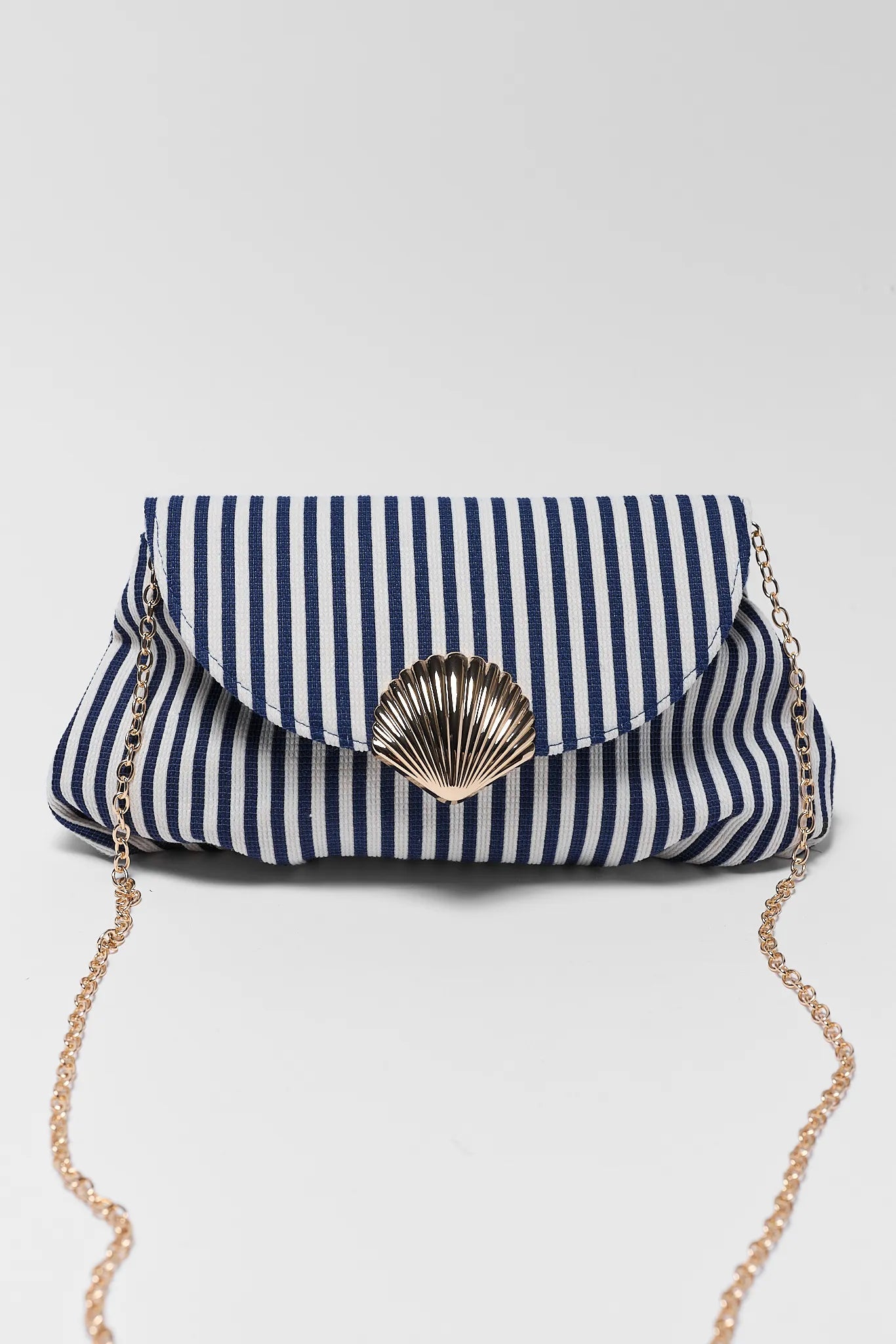 Navy and white striped clutch bag with a gold chain on a light gray background