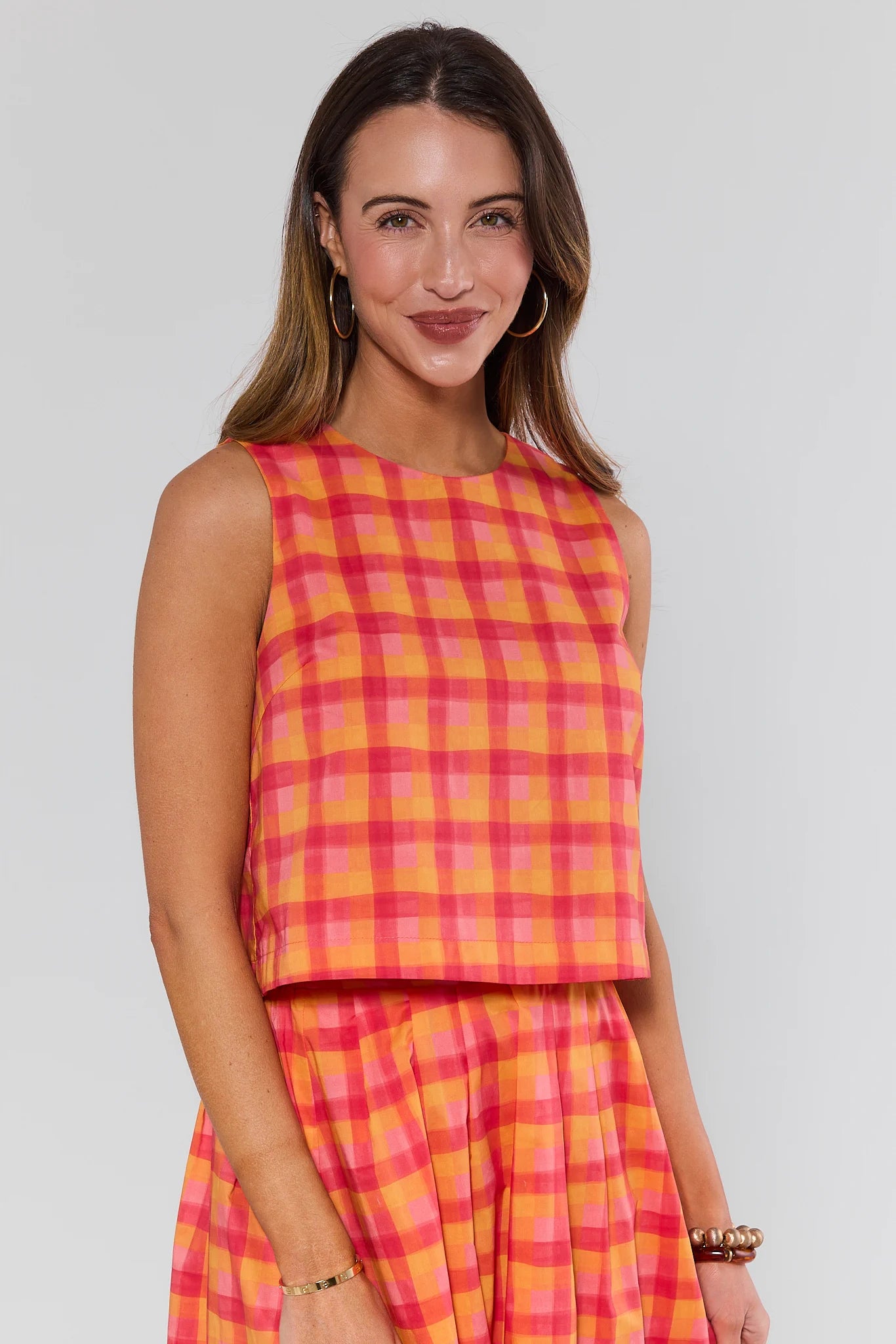 Woman wearing a pink and orange plaid dress on a gray background