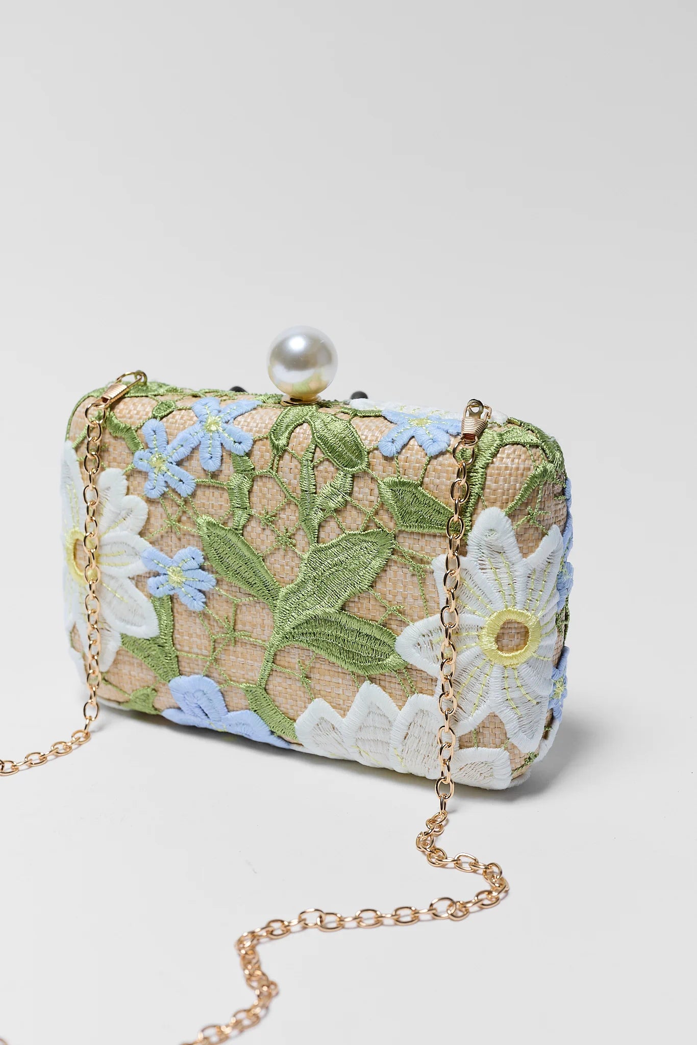 Floral embroidered clutch bag with a pearl embellishment on a white background
