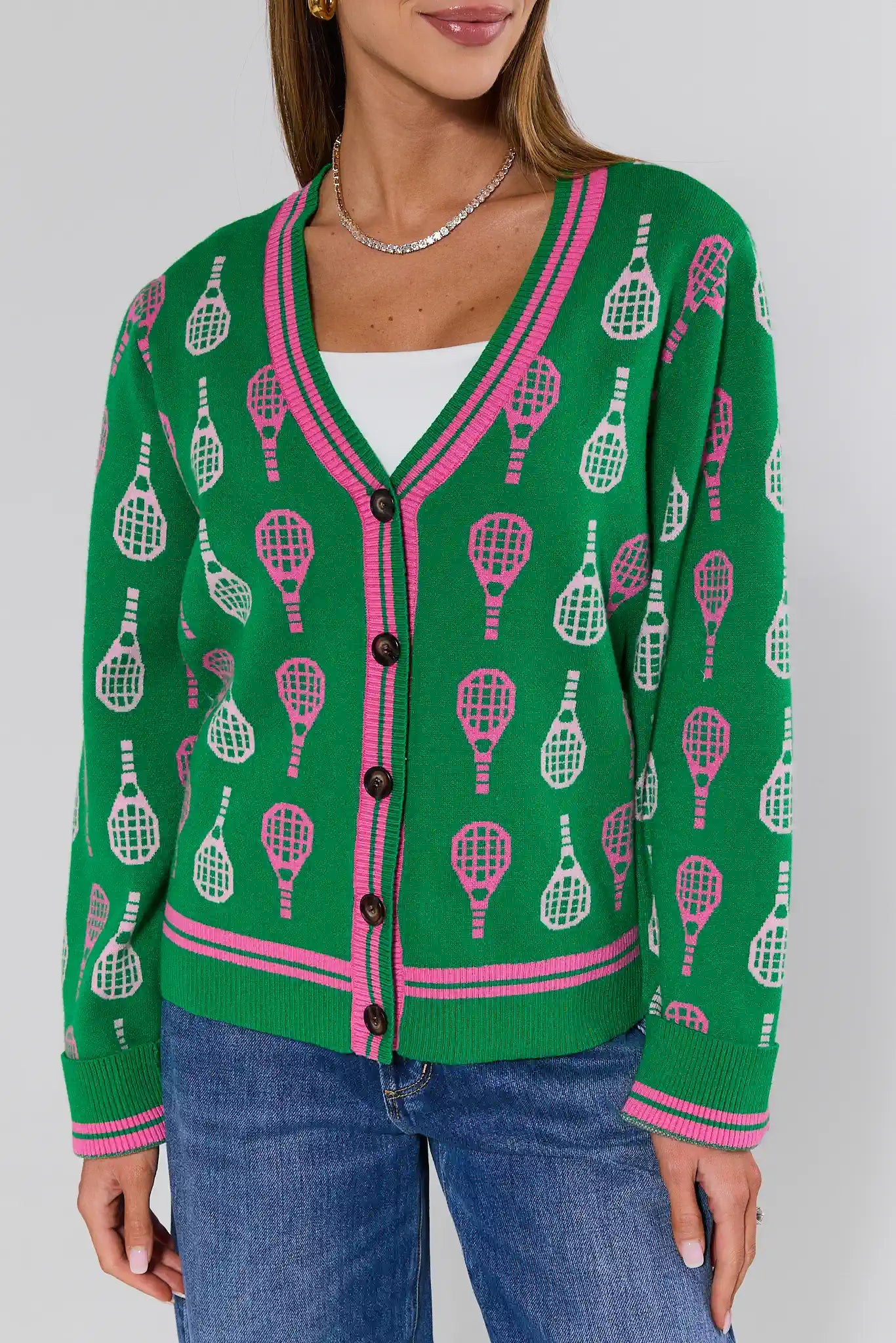 Green cardigan with tennis racket pattern worn by a person on a plain background