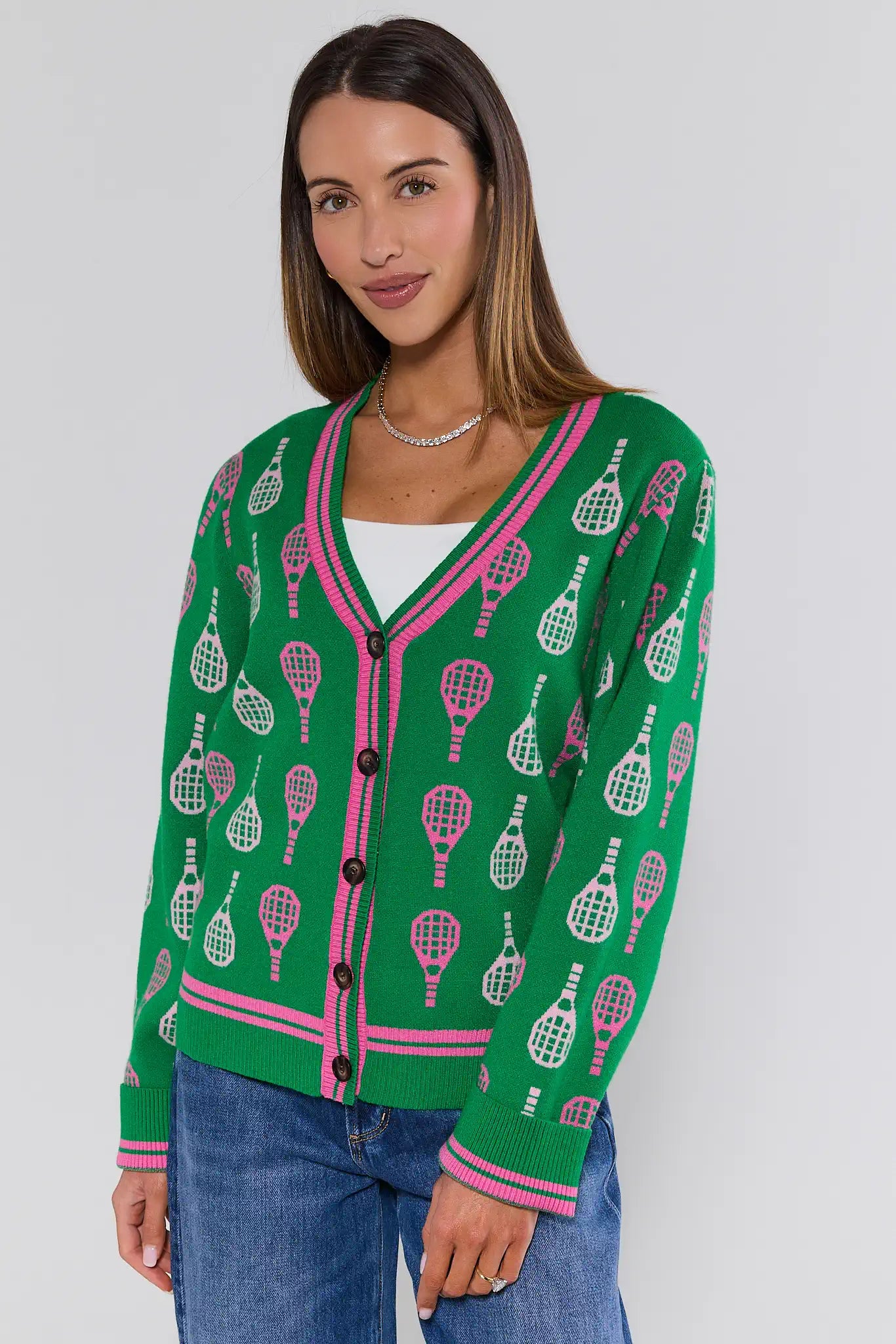 Woman wearing a green cardigan with tennis racket pattern on a white background