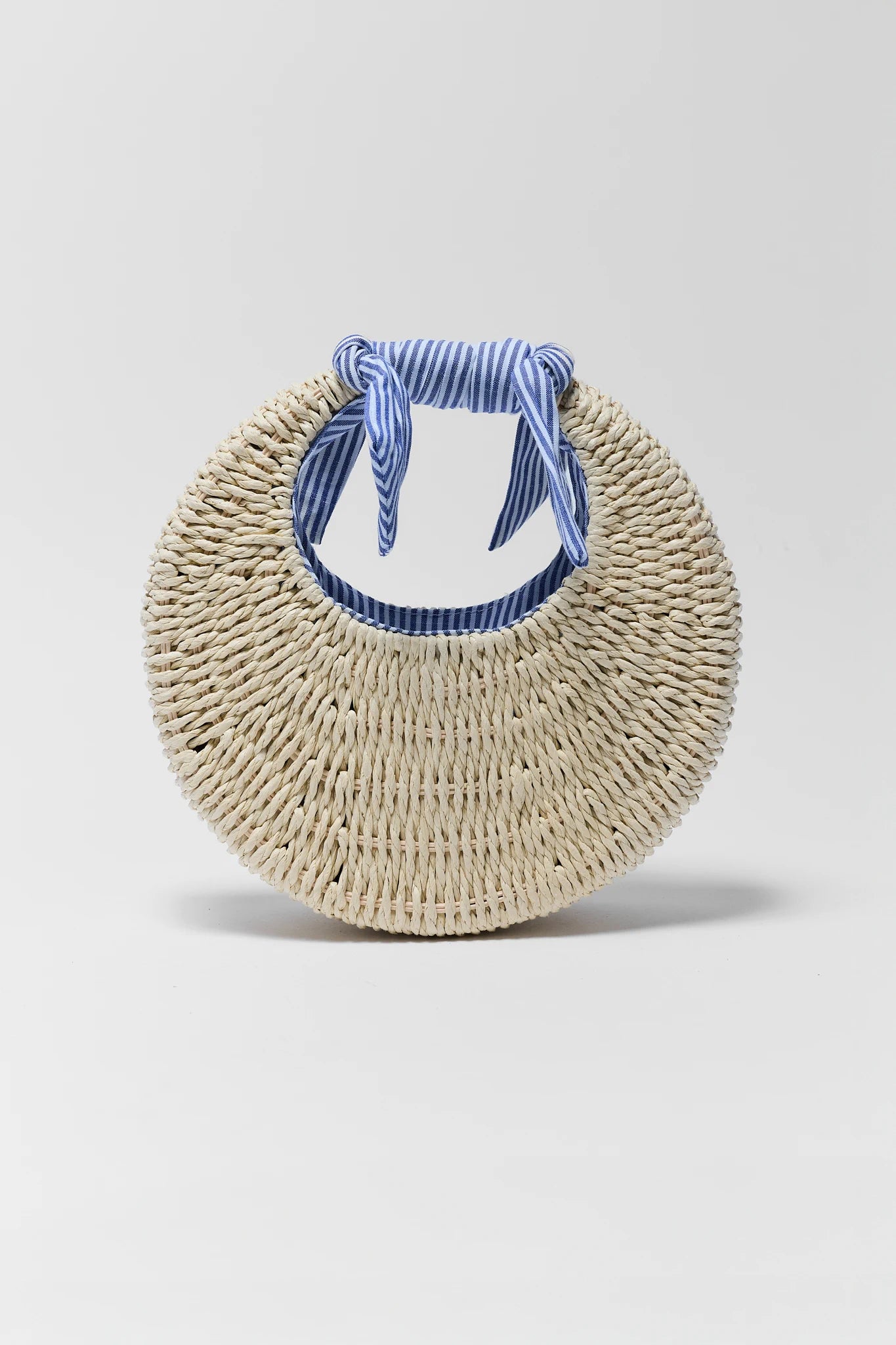 Round woven bag with a blue striped handle on a light gray background
