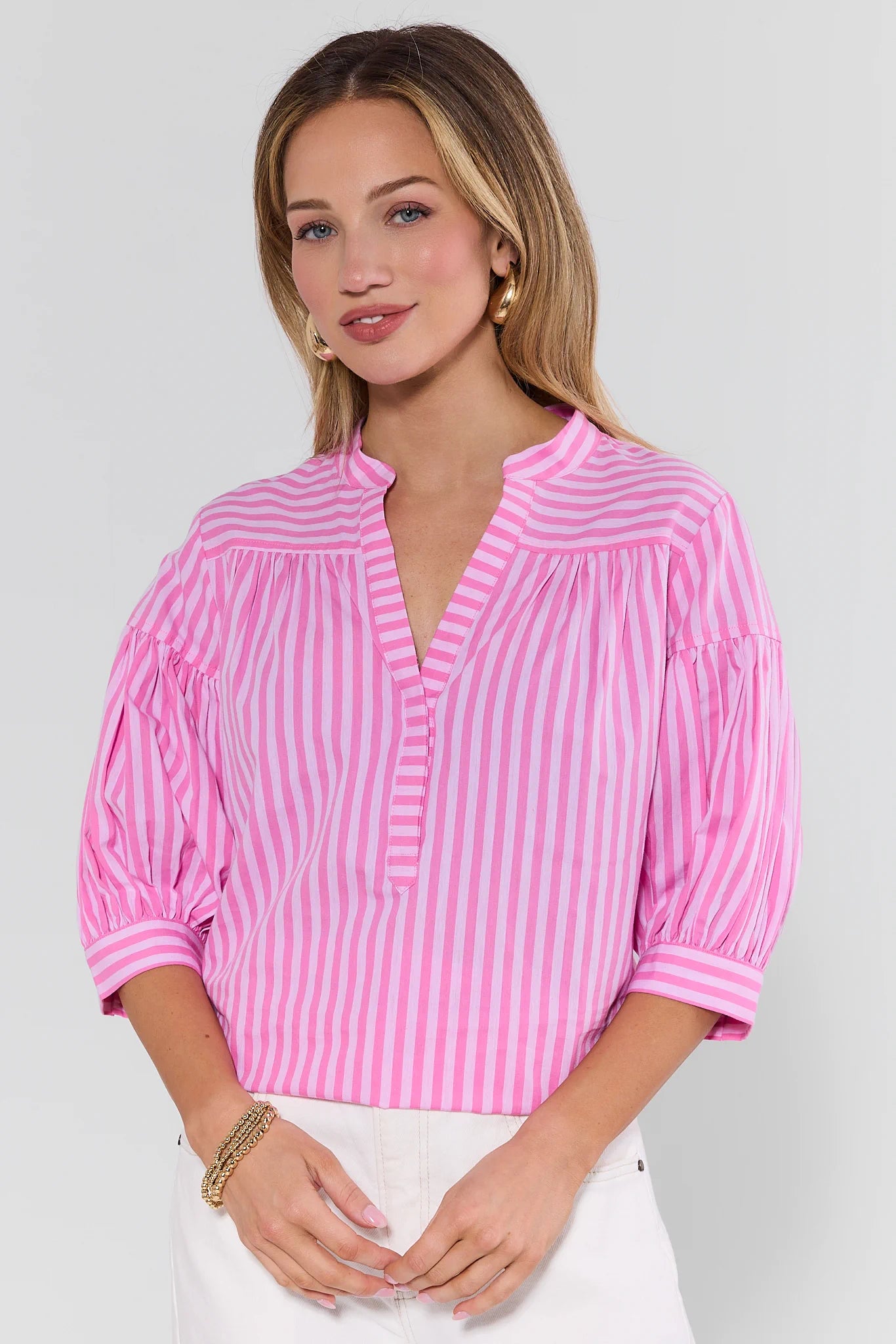 Woman wearing a pink and white striped blouse against a plain background