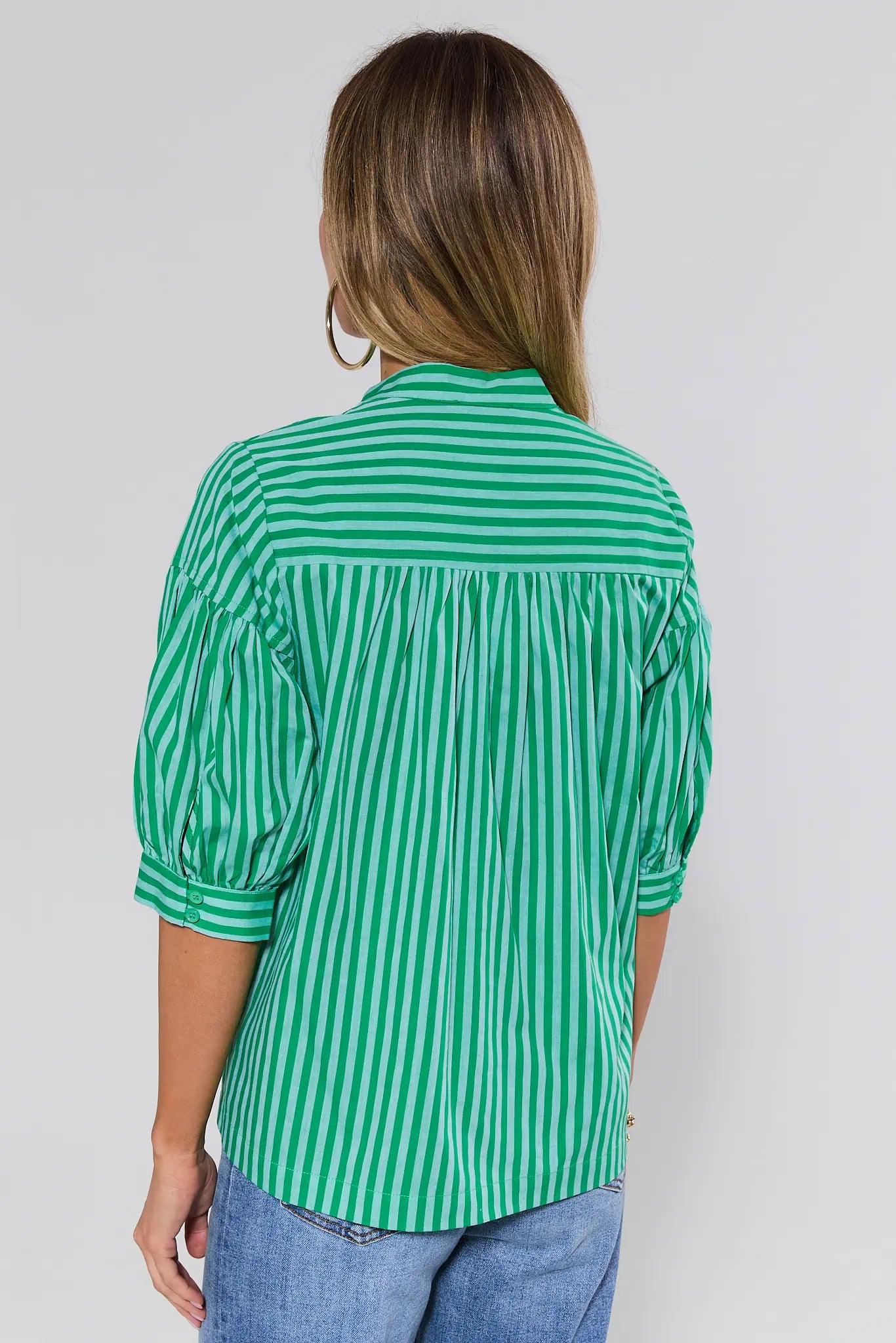 Person wearing a green and white striped shirt on a plain background