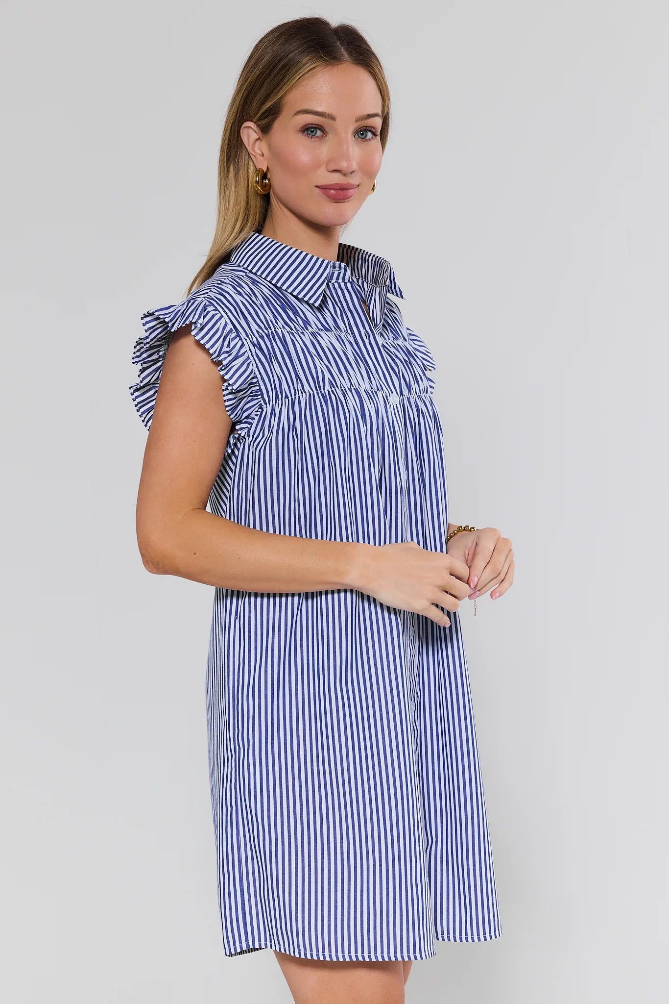 Woman wearing a blue and white striped dress against a plain background