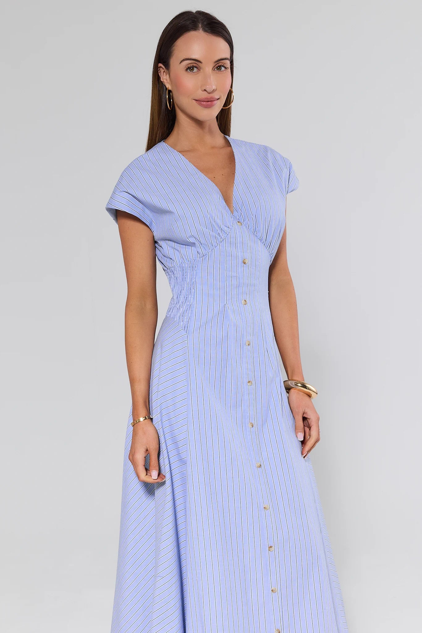 Woman wearing a light blue dress with buttons on a white background