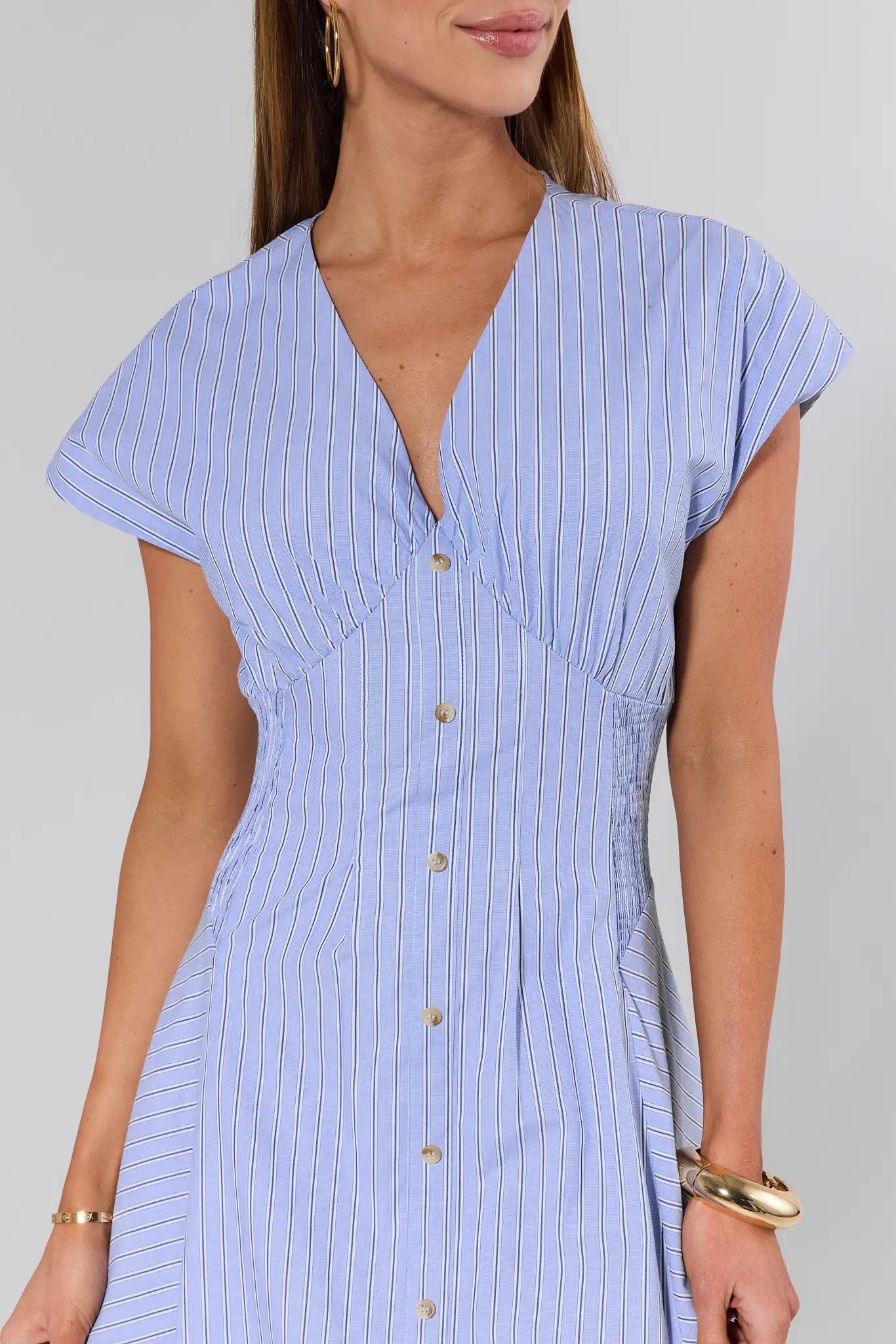 Woman wearing a light blue striped dress with a plain background