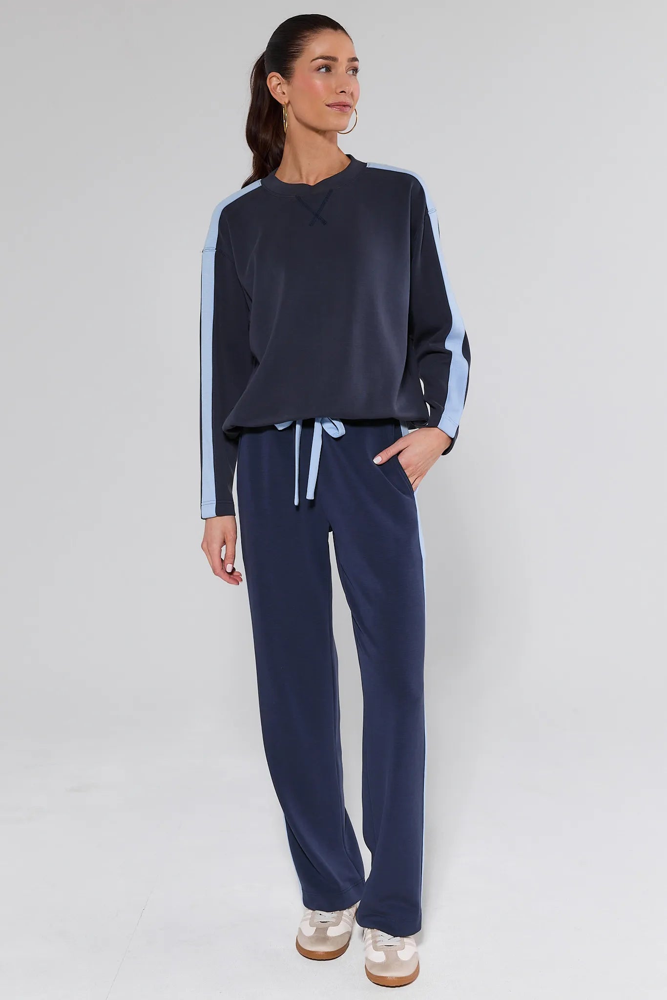 Woman wearing a navy blue outfit with white accents on a light gray background