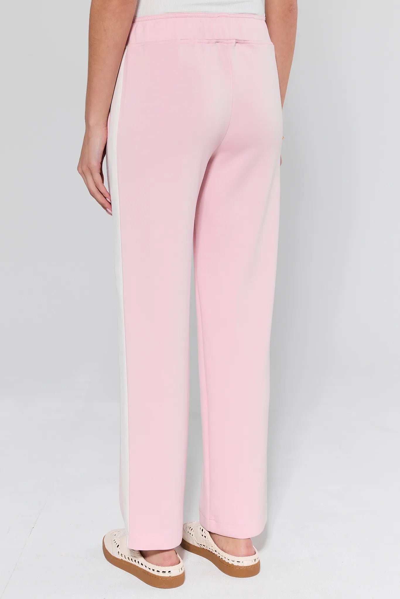 Back view of Katelyn Pink Stripe Lounge Pants featuring a loose fit, white side stripes, elastic waistband, and paired with woven slip-on shoes on a light floor.
