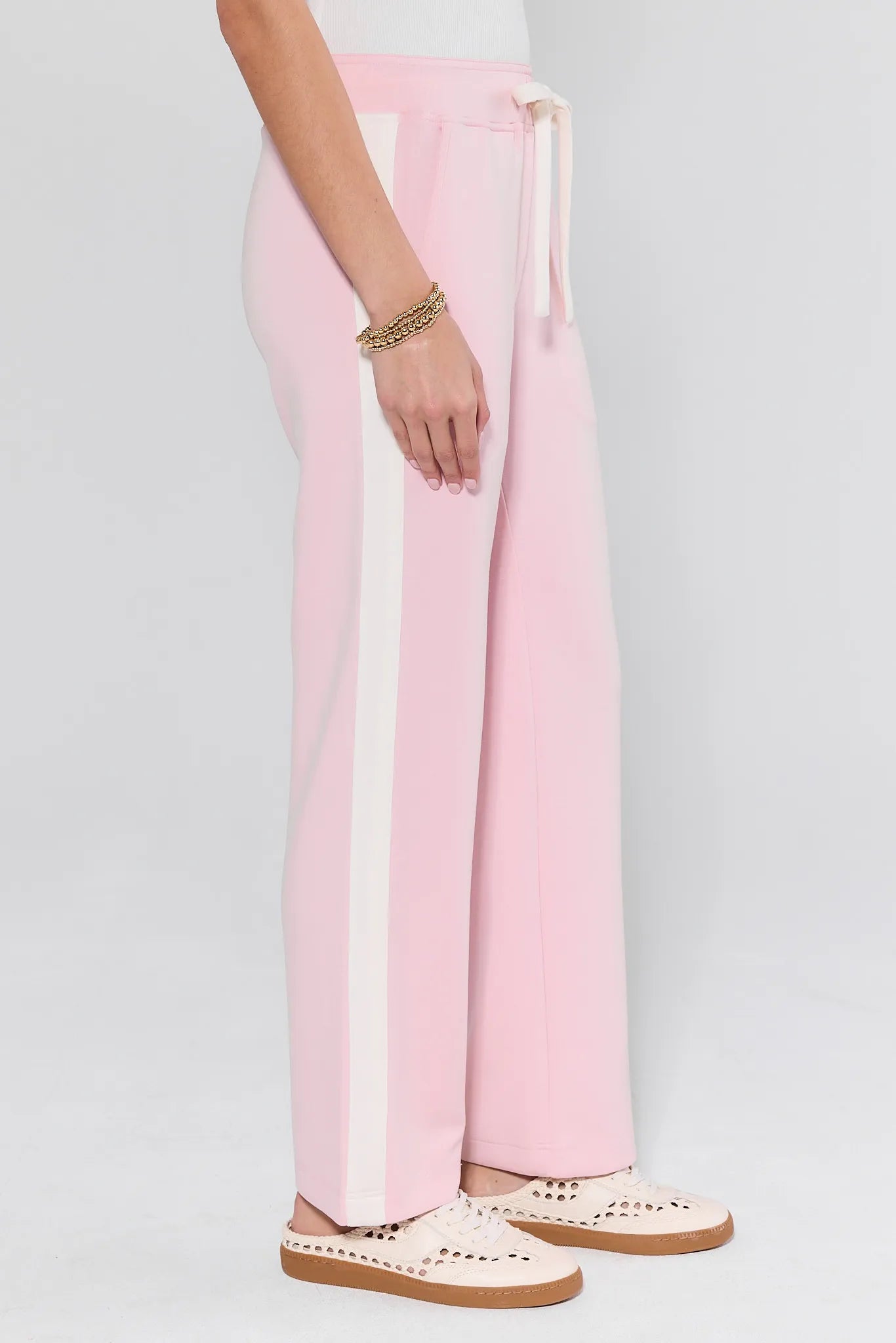 Pink pants with a white stripe worn by a person on a light gray background