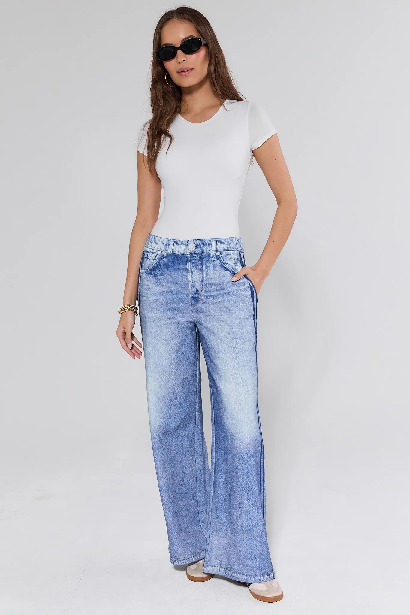 Woman wearing a white t-shirt and blue jeans on a plain background