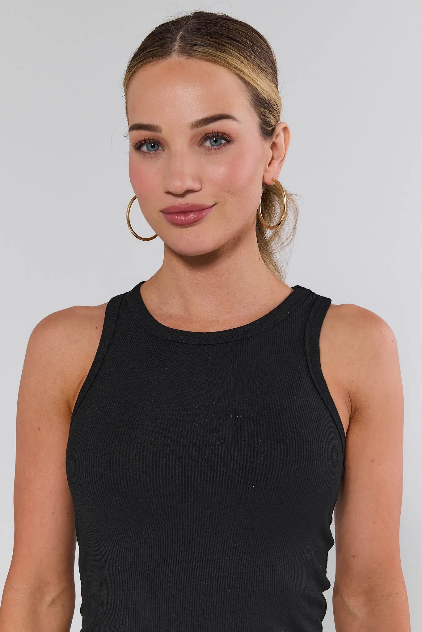 Woman wearing a black allie sleeveless top against a plain background