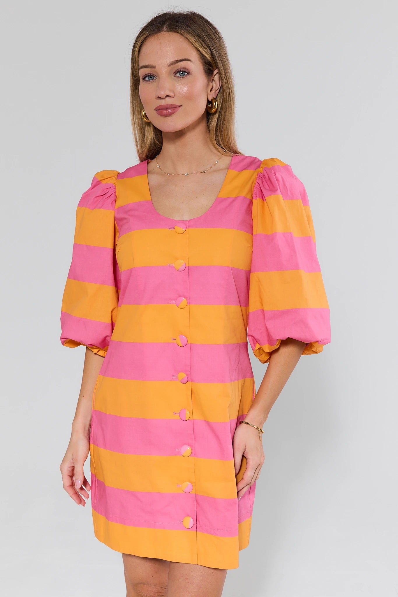 Woman wearing a pink and orange striped dress with puff sleeves on a white background
