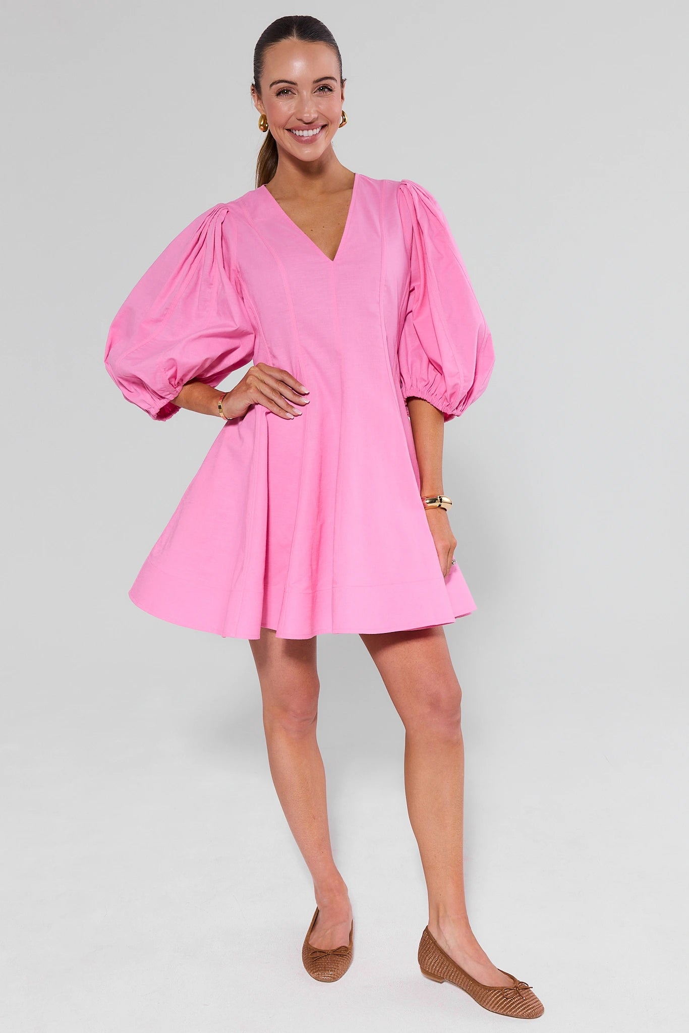 Woman wearing a pink dress with puffed sleeves on a white background