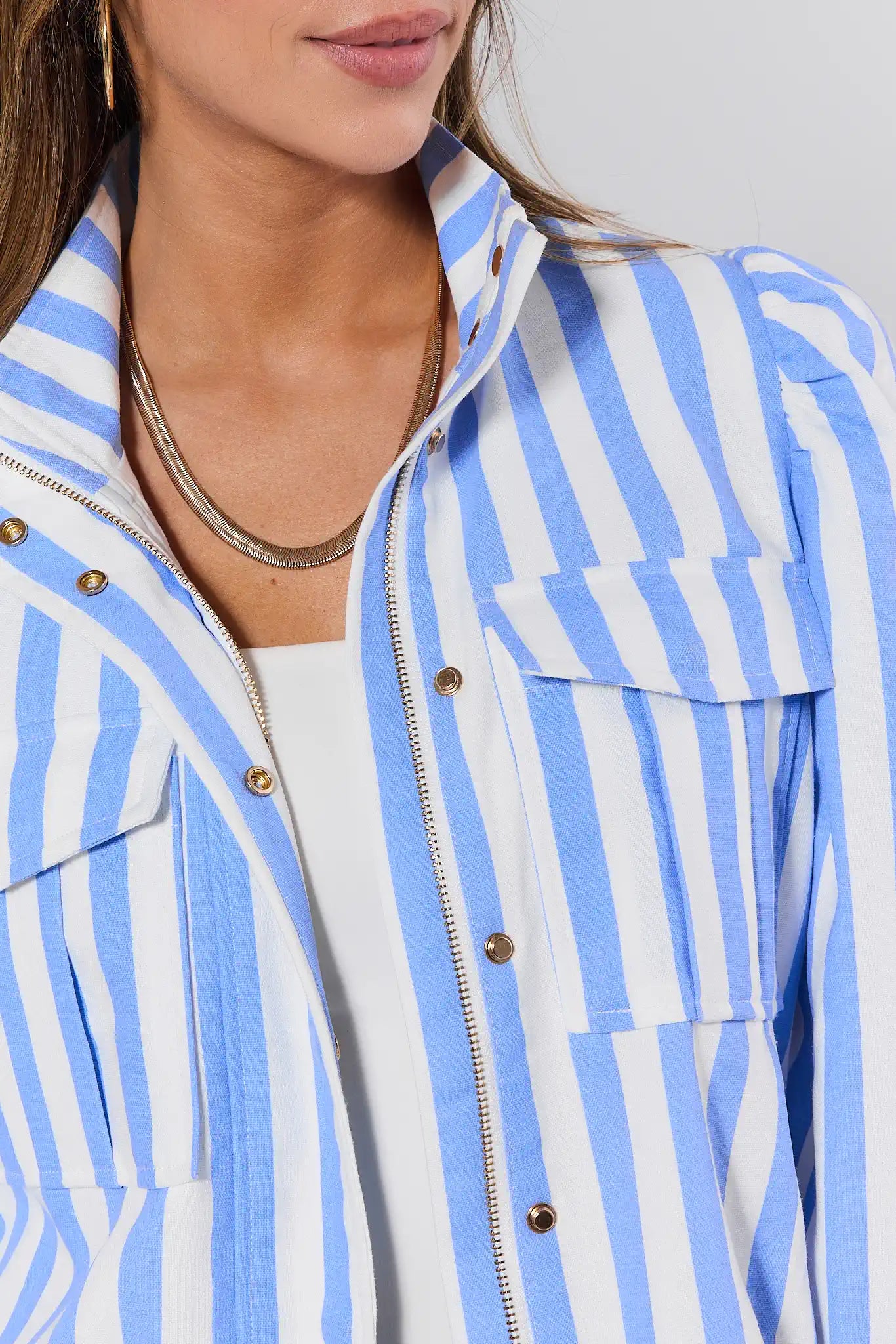 Close-up of a person wearing a blue and white striped jacket with a neutral background