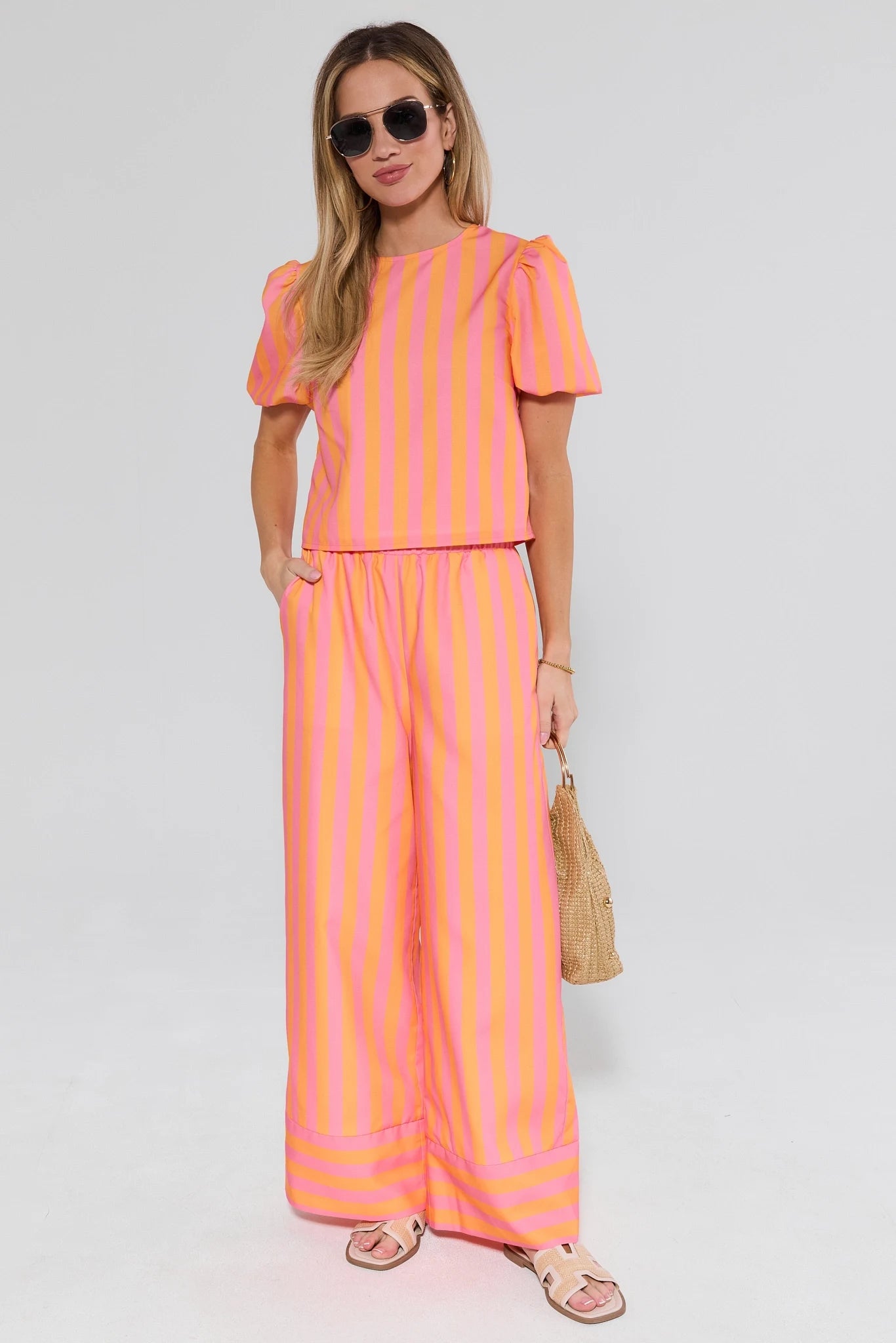 Woman wearing a bright orange and pink striped outfit on a white background