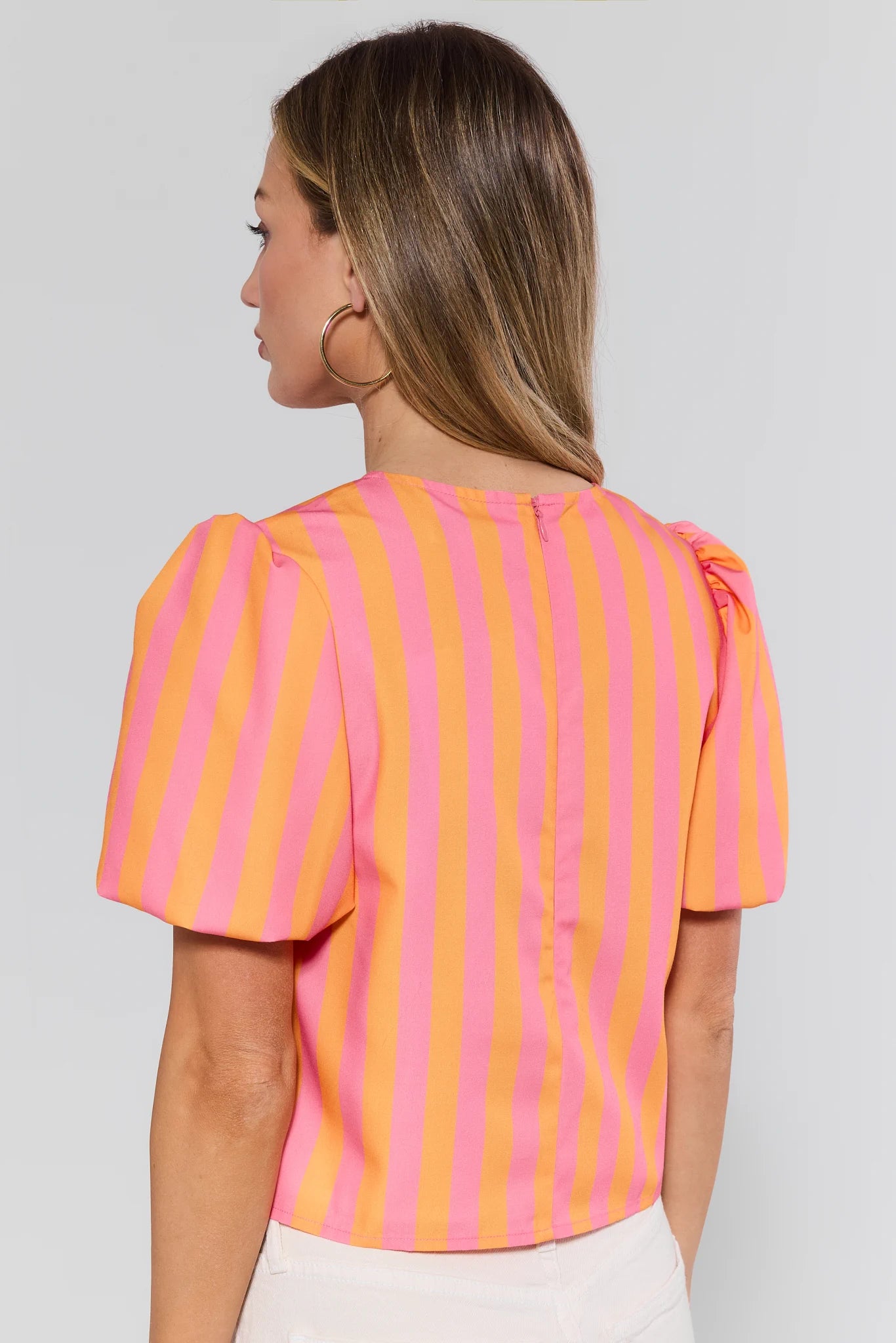Woman wearing a pink and orange striped blouse against a plain background