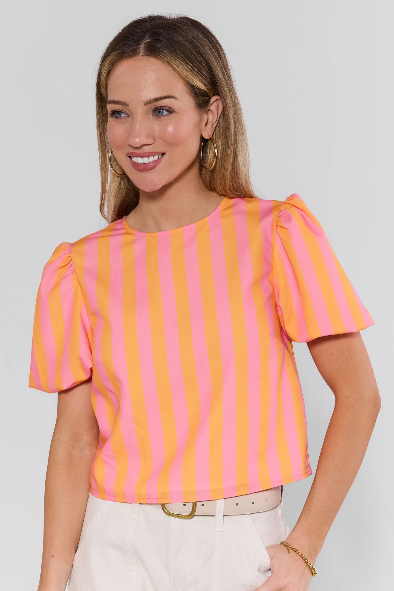 Woman wearing a pink and orange striped top against a plain background