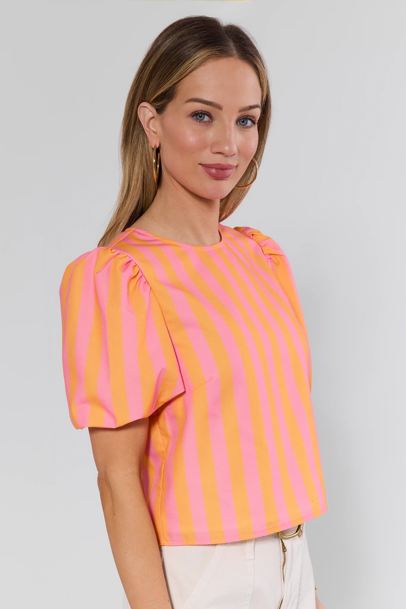 Woman wearing a pink and orange striped top against a plain background