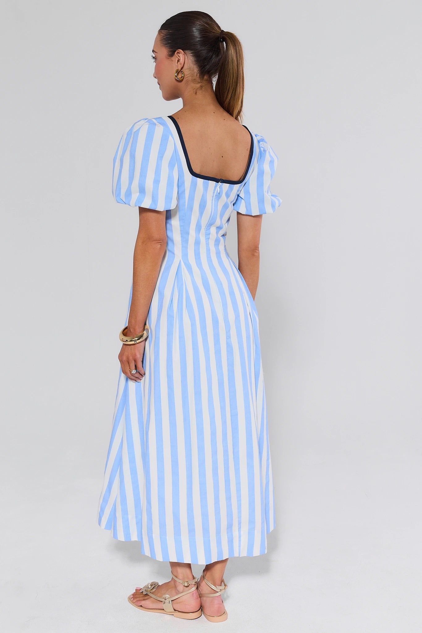 Woman wearing a blue and white striped dress on a plain background