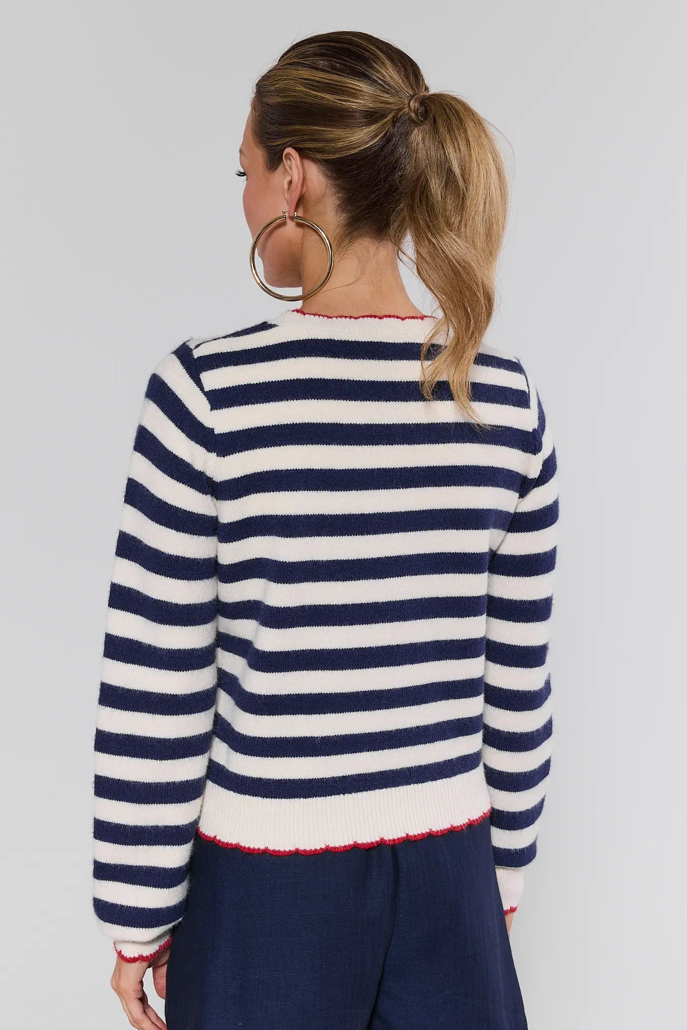 Woman wearing a navy and white striped sweater against a plain background