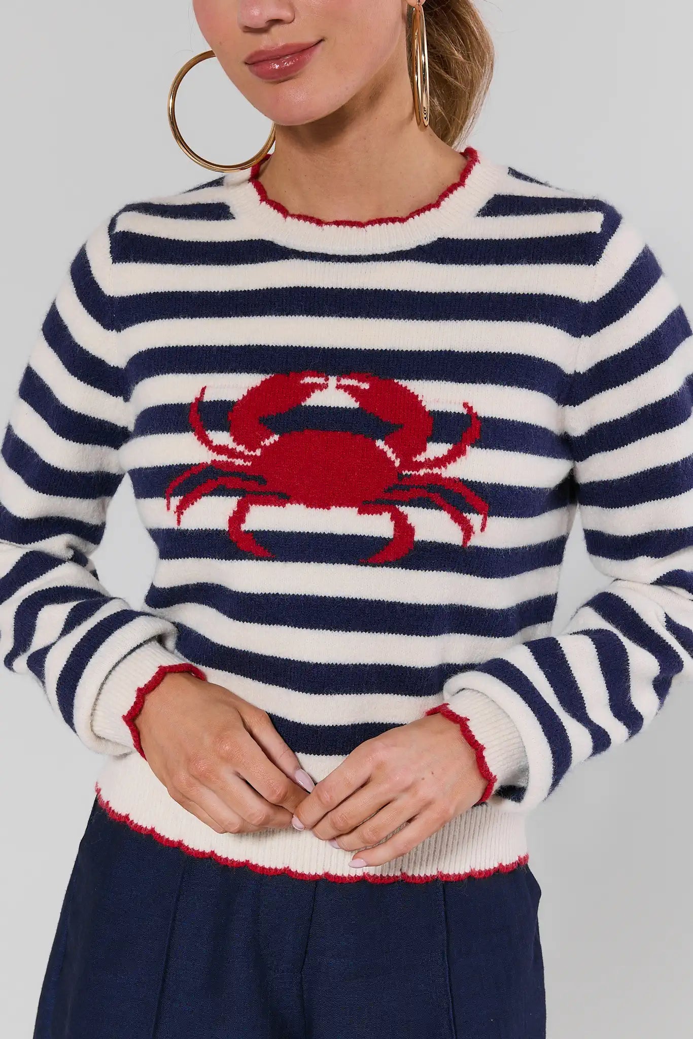 Person wearing a striped sweater with a red crab design on a plain background