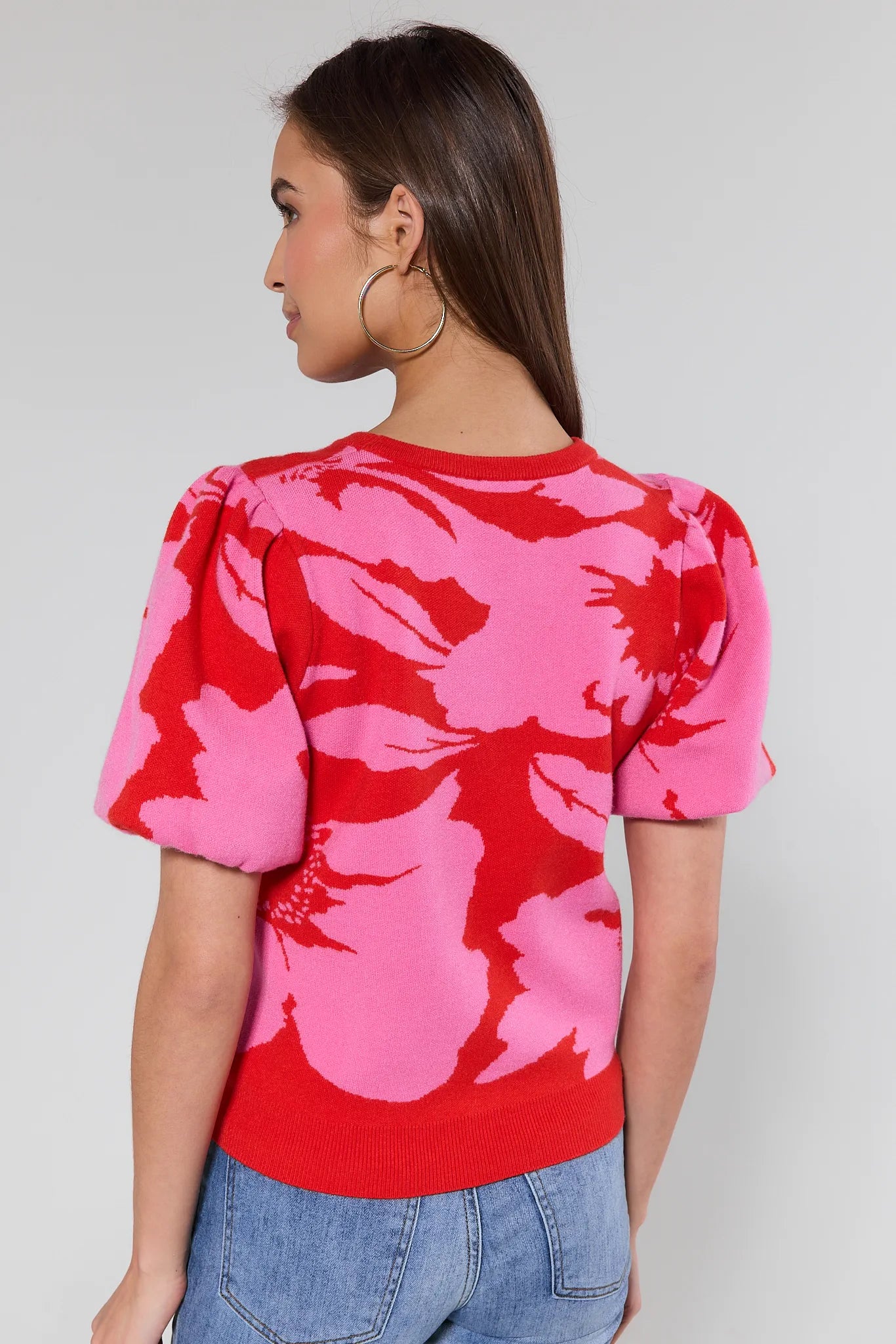woman wearing pink and red floral knit top on a white background