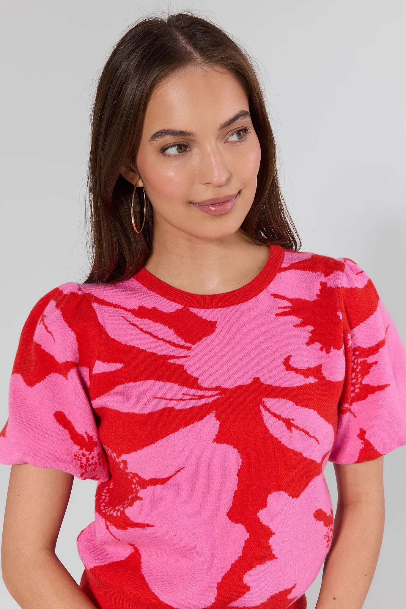 woman wearing pink and red floral short sleeve top on a white background