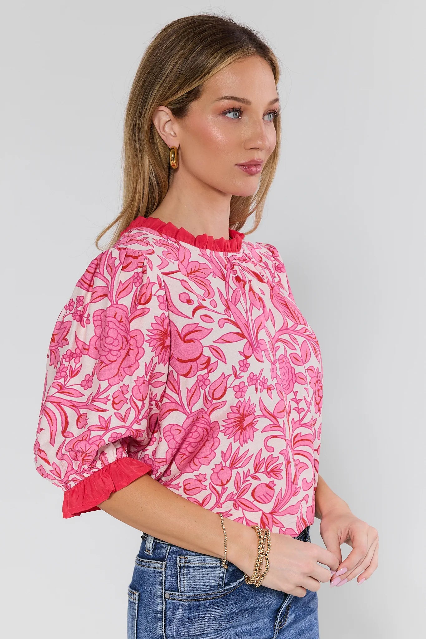 woman wearing a pink floral puff sleeve top on a white background